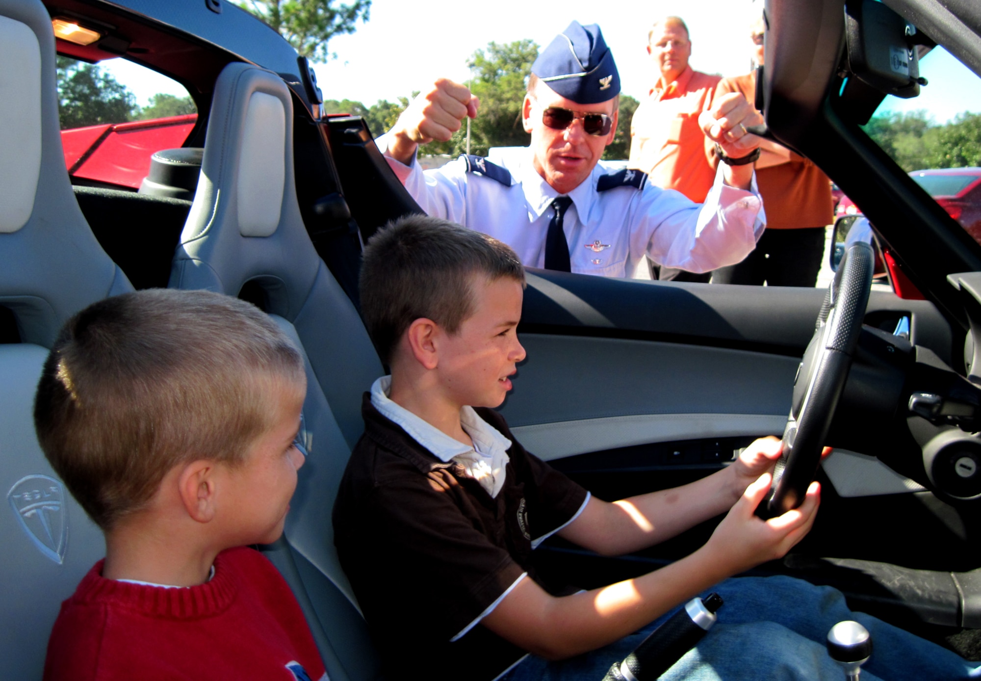 Jimmy and Sean Stover, both winners of Eglin’s Energy Management office energy conservation poster contest, sit in the 2009 Tesla Roadster and listen as Col. Bruce McClintock, 96th Air Base Wing commander, describes his experience driving the Roadster. The poster contest was part of an Energy Expo here Oct. 21 that gave thousands of Main Exchange visitors a look at the future of energy use here. (U.S. Air Force photo/Mike Spaits)