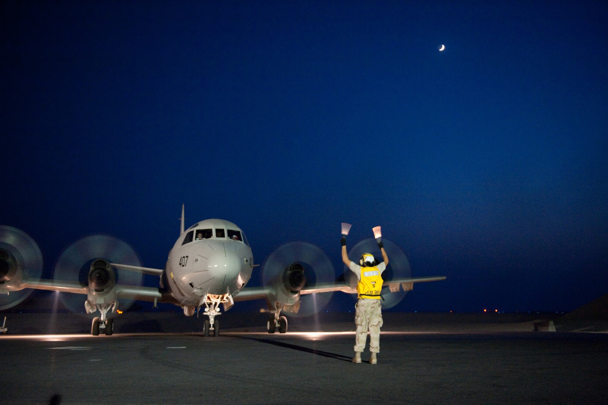 U.S. Navy Aviation Machinist's Mate 3 Ryan Tillar, VP-10, directs a P-3 Orion to a parking spot, Oct. 22, 2009, in Southwest Asia. The P-3 is a land-based, long-range, anti-submarine warfare patrol aircraft performing regular missions in support of Operation Enduring Freedom.  (U.S. Air Force photo/Staff Sgt. Robert Barney) 