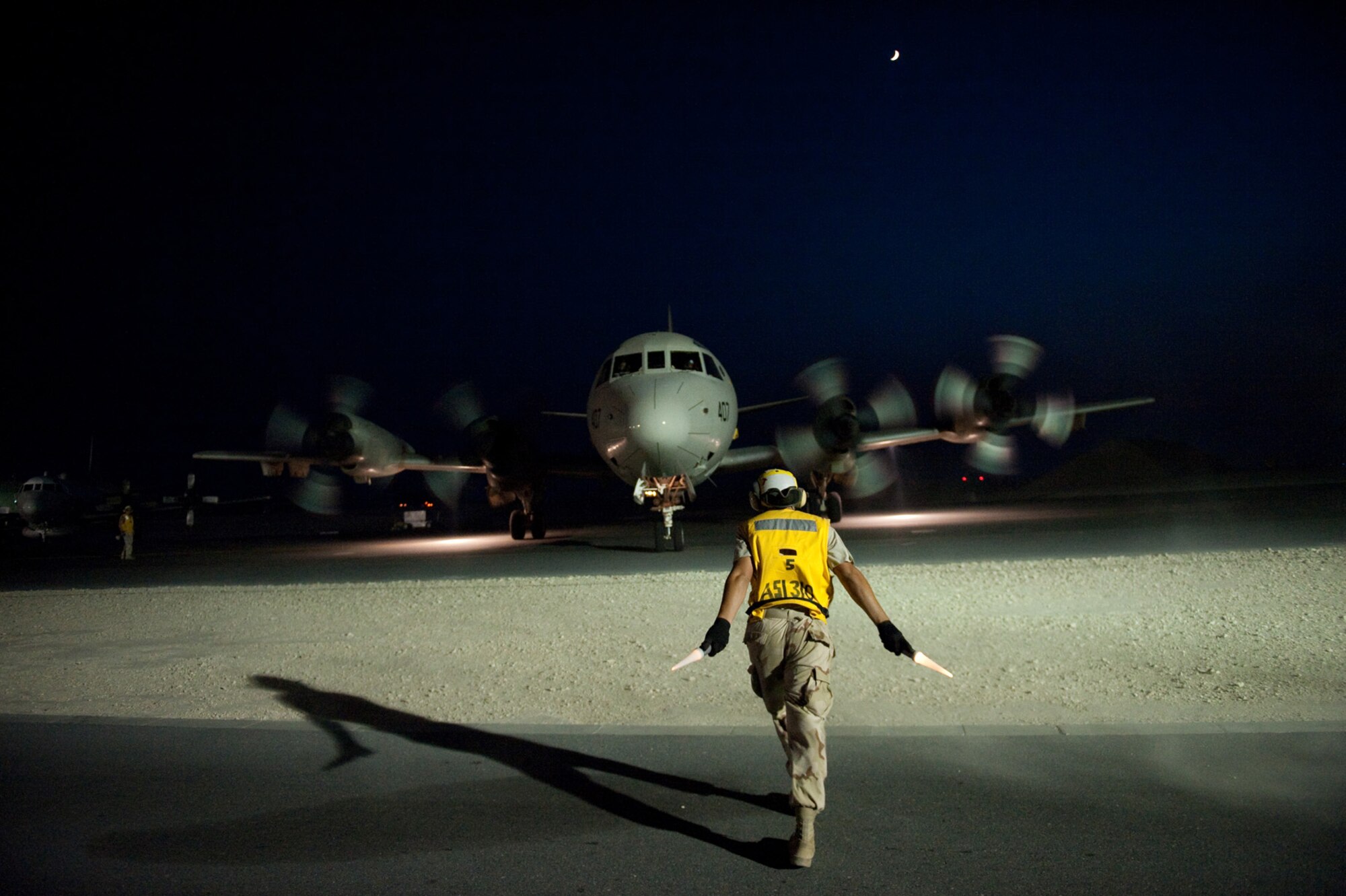 U.S. Navy Aviation Machinist's Mate 3 Ryan Tillar, VP-10, directs a P-3 Orion to a parking spot, Oct. 22, 2009, in Southwest Asia. The P-3 is a land-based, long-range, anti-submarine warfare patrol aircraft performing regular missions in support of Operation Enduring Freedom.  (U.S. Air Force photo/Staff Sgt. Robert Barney) 