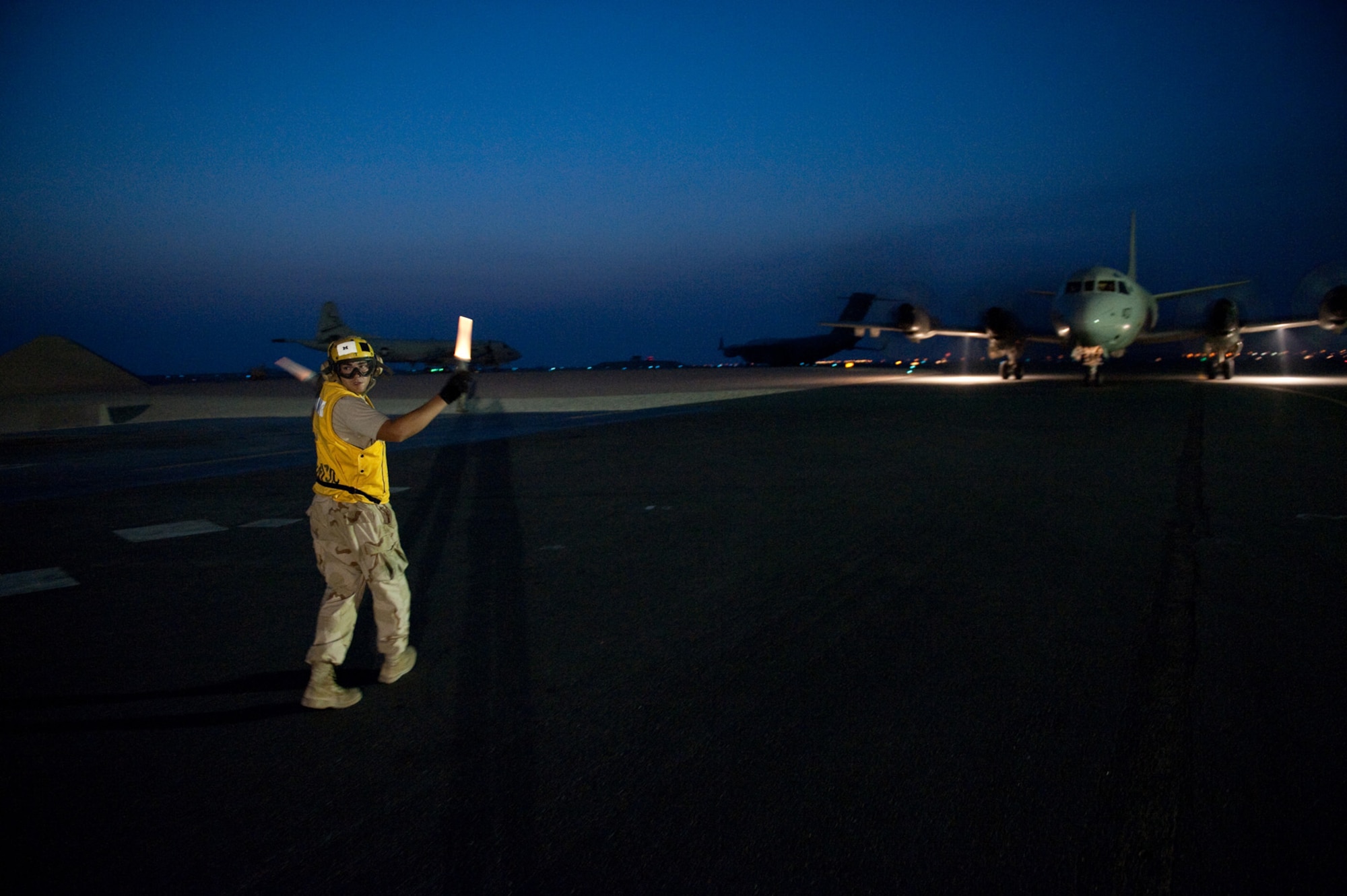 U.S. Navy Aviation Machinist's Mate 3 Ryan Tillar, VP-10, directs a P-3 Orion to a parking spot, Oct. 22, 2009, in Southwest Asia. The P-3 is a land-based, long-range, anti-submarine warfare patrol aircraft performing regular missions in support of Operation Enduring Freedom.  (U.S. Air Force photo/Staff Sgt. Robert Barney) 