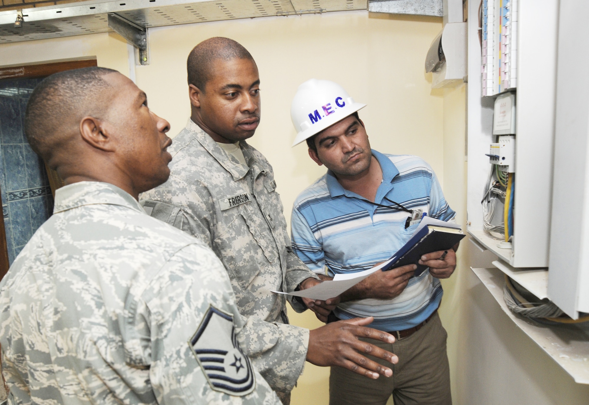 Master Sgt. Tommy Robinson (left) and Navy Petty Officer 2nd Class Jack Frierson (center) inspect an electrical panel installed by Iraqi contractors during a renovation project in the International Zone Oct. 18, 2009, in Baghdad, Iraq. The NCOs are responsible for ensuring Iraqi contractors awarded construction projects follow contract agreements, safety rules and national electric codes. Sergeant Robinson is deployed from Luke Air Force Base, Ariz., and is a native of Graceville, Fla. Petty Officer Frierson is deployed from Norfolk Naval Air Station, Va., and hails from Kingtree, S.C. The two are joint area support group department of public works Team 2 NCOs. (U.S. Air Force photo/Tech. Sgt. Johnny L. Saldivar) 