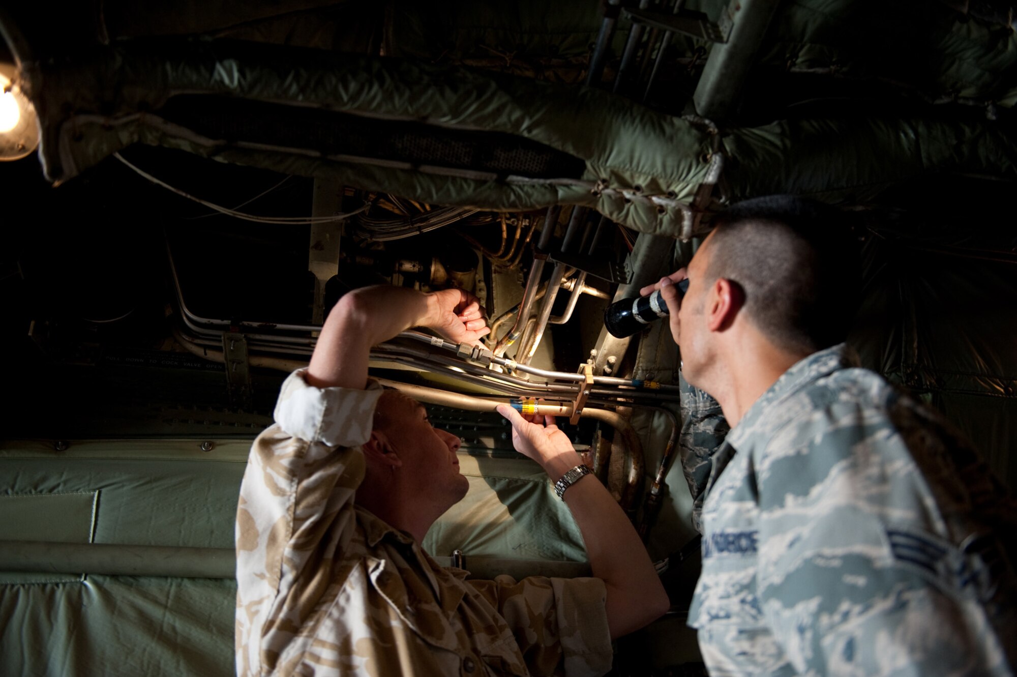 Right, Senior Airman Spencer Hensinger, 379th Expeditionary Maintenance Squadron fabrication flight, and Royal Air Force Chief Technician Dave Darley work together to replace a hydraulic line on a C-130, Oct. 21, 2009 in Southwest Asia. Airman Hensinger helped to fabricate a hydraulic line splice, enabling the RAF to maintain mission completion in providing airlift support throughout Southwest Asia. (U.S. Air Force photo/Staff Sgt. Robert Barney) 