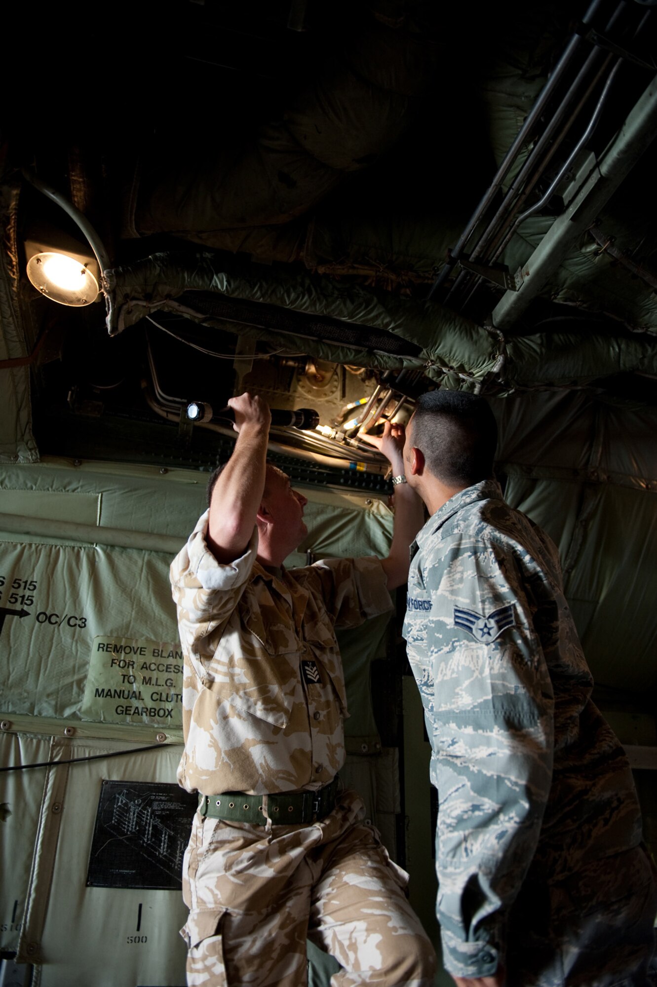 Right, Senior Airman Spencer Hensinger, 379th Expeditionary Maintenance Squadron fabrication flight, and Royal Air Force Chief Technician Dave Darley work together to replace a hydraulic line on a C-130, Oct. 21, 2009 in Southwest Asia. Airman Hensinger helped to fabricate a hydraulic line splice, enabling the RAF to maintain mission completion in providing airlift support throughout Southwest Asia. (U.S. Air Force photo/Staff Sgt. Robert Barney) 