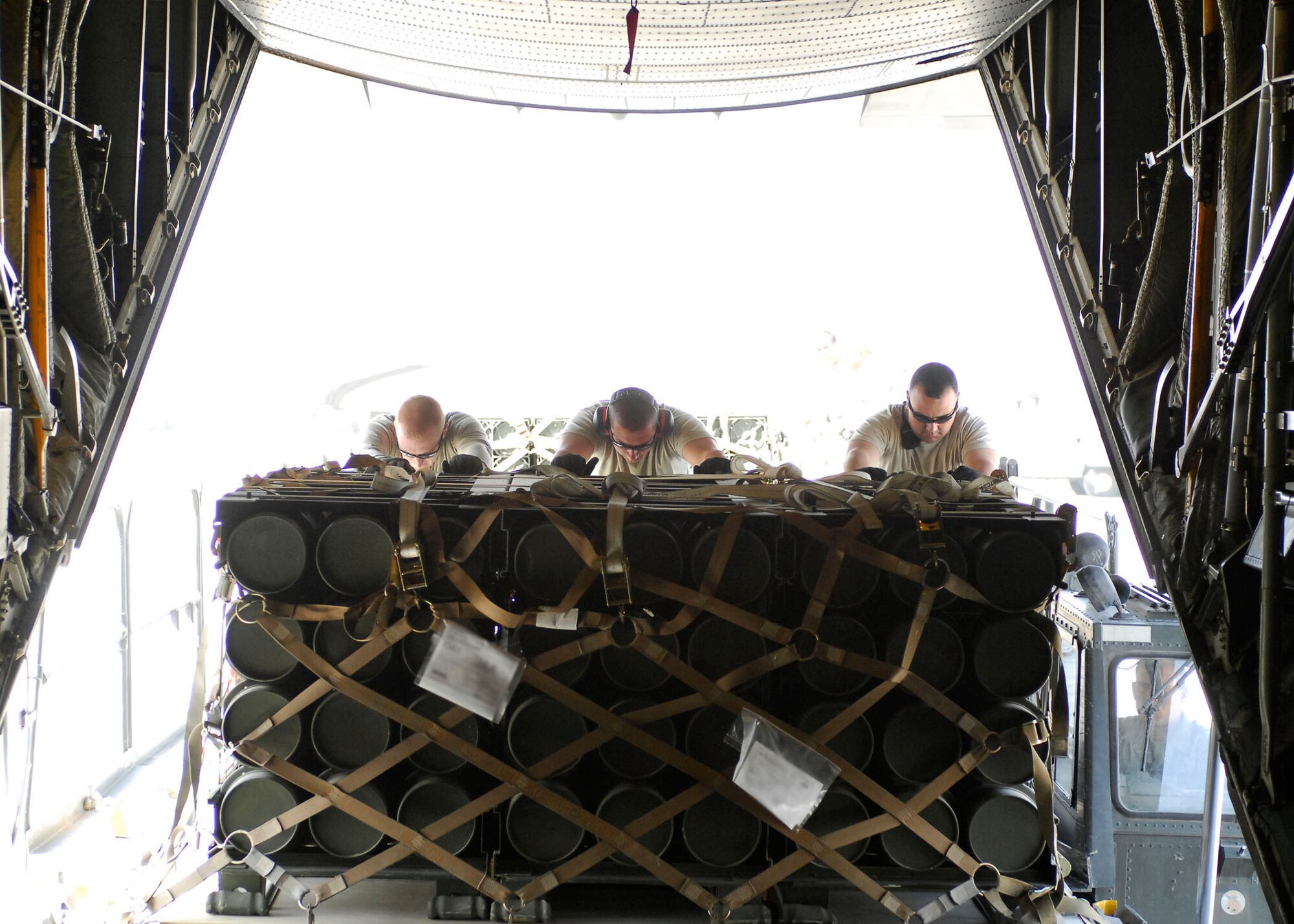 BAGRAM AIRFIELD, Afghanistan -- From left to right Staff Sgt. Joe Brummett, Master Sgt. Shannon Koenigstein, and Tech. Sgt. Pete Cervantez, all air transportation specialists from the455th Expeditionary Aerial Port Squadron, push pallets of ammunition onto a C-130 Hercules, Oct. 23, 2009.  Sergeant Brummett and Sgt. Cervantez are deployed from Lackland Air Force Base, Texas.  Sergeant Brummett hails from San Antonio, and Sgt. Cervantez hails from Del Rio, Texas.   Sergeant Koenigstein is deployed from McGuire AFB, N.J., and hails from Glennville, Ga.  (U.S. Air Force photo/Senior Airman Felicia Juenke)