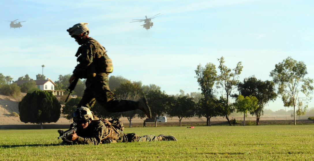 A Marine with Headquarters and Service Company, 1st Battalion, 2nd Marine Regiment, runs to post security as Lance Cpl. Michael Jackson, motor transportation operator, watches the perimeter of Kiwanis Park in Yuma, Ariz., as a CH-53E Super Stallion and an Army CH-47 Chinook descend during a noncombatant evacuation operation Oct. 23, 2009. The exercise is part of the Weapons and Tactics Instructors course and takes place in the city of Yuma to provide Marines a realistic urban setting. WTI is hosted biannually at the Marine Corps Air Station in Yuma, Ariz. Jackson’s battalion participated in the exercise in preparation for their deployment to Afghanistan early next year. Jackson, 19, is a Baltimore native.