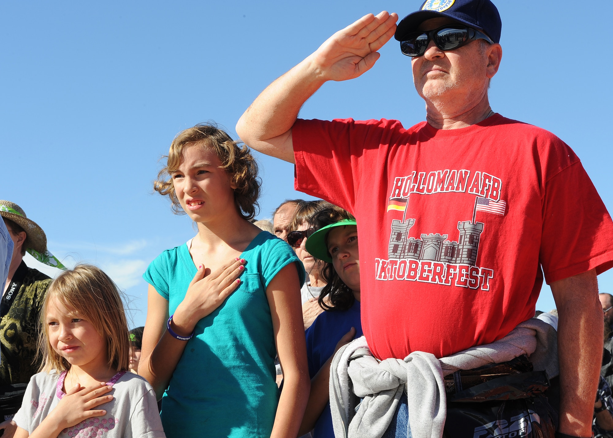 HOLLOMAN AIR FORCE BASE, N.M. -- Patrons of the ?Raptors and Reapers over the Southwest? open house render proper respect during the National Anthem here, Oct. 24.  While aerial acts were performed, patrons were able to buy food, drinks, squadron memorabilia and souvenirs. Children were able to enjoy the Kid?s Zone complete with bouncing castles, face painting and the chance to meet a pilot (U.S. Air Force photo by Senior Airman John D. Strong II) 