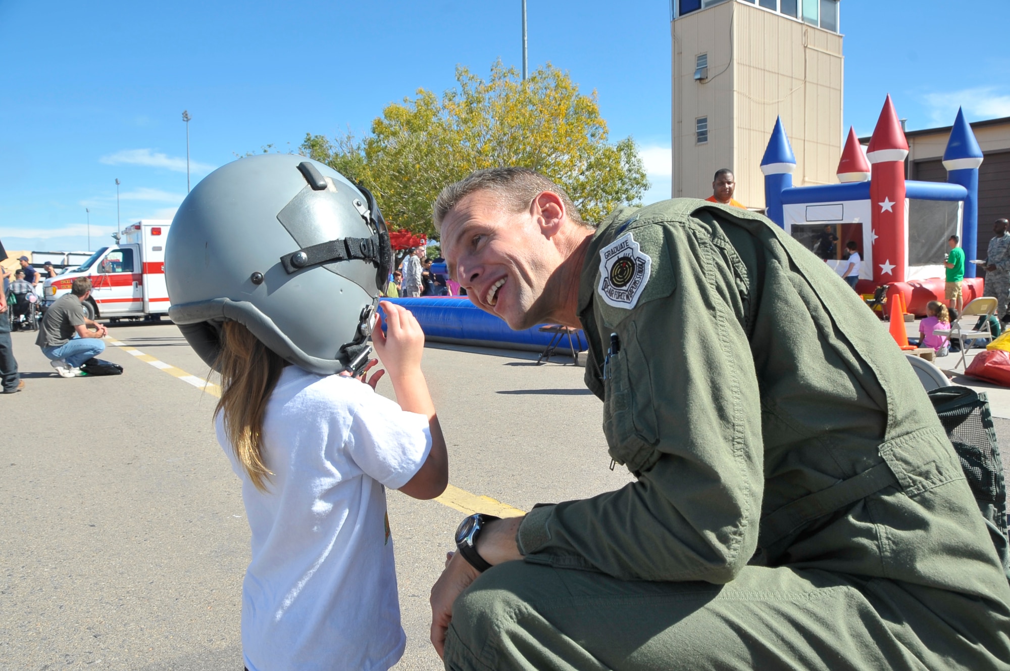 HOLLOMAN AIR FORCE BASE, N.M. -- Col. Michael Stapleton, 49th Operations Group commander, fits a young open house patron with the helmet worn by fighter pilots when they fly at the 2009 Open House here Oct. 24. The Holloman Open House showcased military and civilian aircraft. (U.S. Air Force photo by Tech. Sgt. Chris Flahive)
