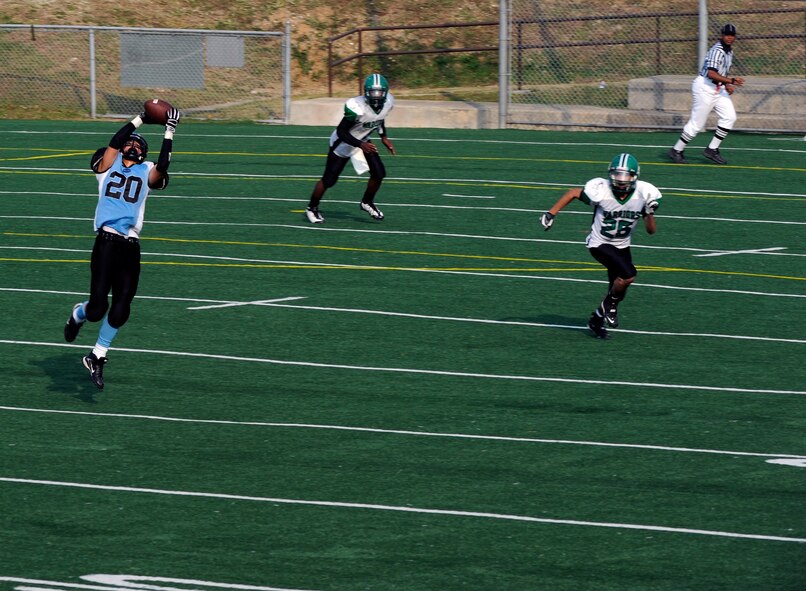 Osan American High School running back Paul Snead makes a leaping catch while Daegu American School defensive back David Martinez (25) pursues for a tackle during the teams' game Oct. 24 at Osan Air Base. OAHS broke open a tight game early in the fourth quarter and held on to win 28-26. The teams will play again Oct. 30 at DAS for a chance to advance to the Far East Korea Small Schools playoff. (U.S. Air Force Photo by 1st Lt. Chris Hoyler)