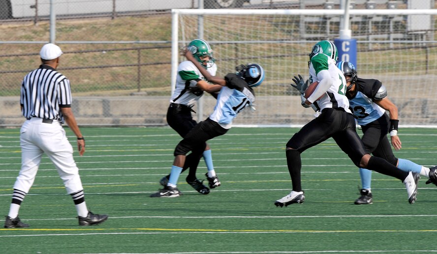 Daegu American School running back Mychael Goodson, right with ball, tries to get around the outside while Osan American High School linebacker Luke Travis pursues a takcle during the teams' game at Osan Air Base Oct. 24. In the background, DAS wide receiver Christian Dawes blocks OAHS defensive back Ibrahim Mustapha. OAHS won 28-26 to force a rematch Oct. 30 at DAS for a chance to advance to the Far East Korea Small Schools playoff. (U.S. Air Force Photo by 1st Lt. Chris Hoyler)