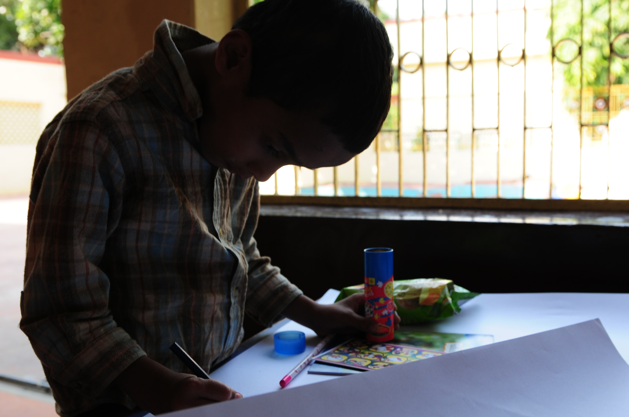 A Indian boy sits and immediately begins coloring on butcher paper after receiving donated art supplies from more than 150 Airmen and Soldiers who visited the Mother Teresa orphanage in Agra, India, Oct. 22. The Airmen and Soldiers volunteered their time with children and the elderly and donated cash, school supplies, food, and clothing during their visit. Cope India is a United States and India airlift exercise that provides training for humanitarian assistance and disaster relief operations. (U.S. Air Force photo/Capt. Genieve David)