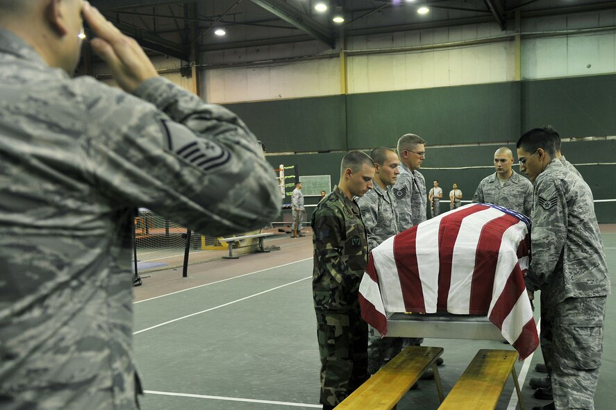 Master Sgt. David Schmidt, Offutt Air Force Base honor guard, Neb. administers military honors while other base honor guard members carry the casket during a training session on Offutt Oct. 21. United States Air Force Honor Guard trainers visited Offutt to evaluate and help sharpen the skills of base honor guard members. (U.S. Air Force photo by Charles Haymond) 