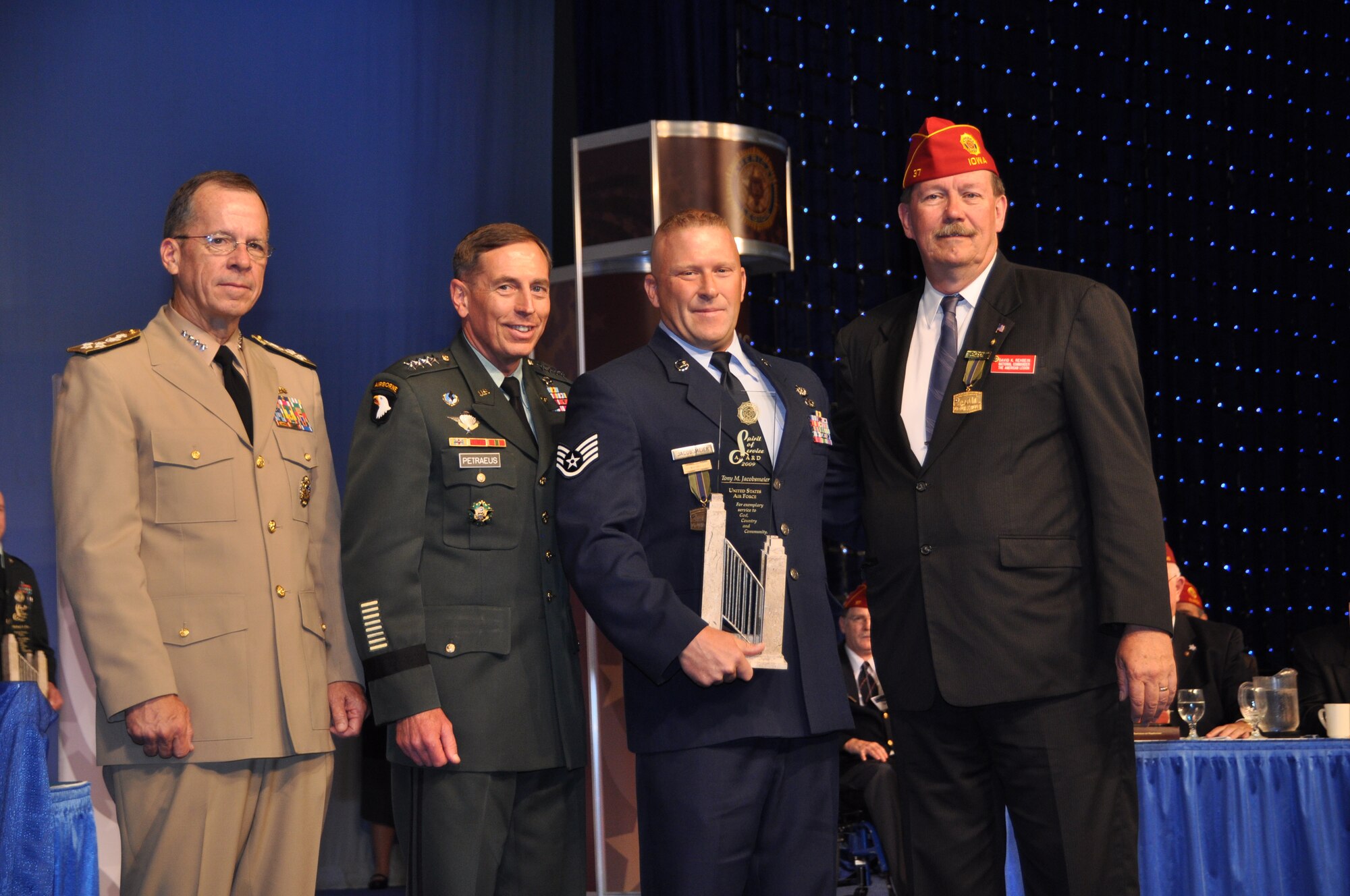 LOUSIVILLE, Ky. -- Staff Sgt. Tony Jacobsmeier, 15th Civil Engineer Squadron 'Dirt Boy,' was presented the American Legion Spirit of Service Award Aug. 25 by (left to right) Admiral Michael, Chairmen of the Joint Chiefs of Staff; General David H. Petraeus, commander, U.S Central Command; and David Rehbein National Commander of American Legion. He and four other military servicemembers, one from each branch of service, were honored at the 91st National Convention in Louisville, Ky. To receive this recognition, an individual must be an outstanding military professional, actively involved in community volunteer projects during off-duty hours.