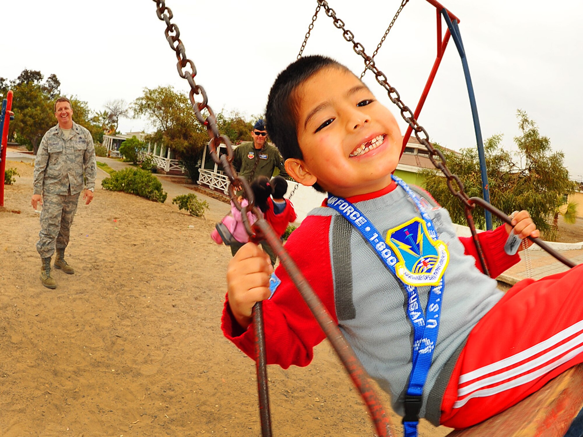 A child proudly displays his 612th Air Operations Center patch as Lt Col Pete Schneider, 159 Fighter Wing Maintenance Group commander, pushes him on a swing at the Aldeas SOS orphanage in Antofagasta, Chile.  The colonel was part of a more than 40 person team of US, Chilean and Argentine Air Force members who visited the charitable organization for orphaned and abandoned children on Sunday.  Airmen took time off from exercise SALITRE, a five-nation exercise aimed at improving coaltion interoperability during peacekeeping operations to reach out to area children with an afternoon of fun and games. (U.S. Air Force photo by Master Sgt. Daniel Farrell)