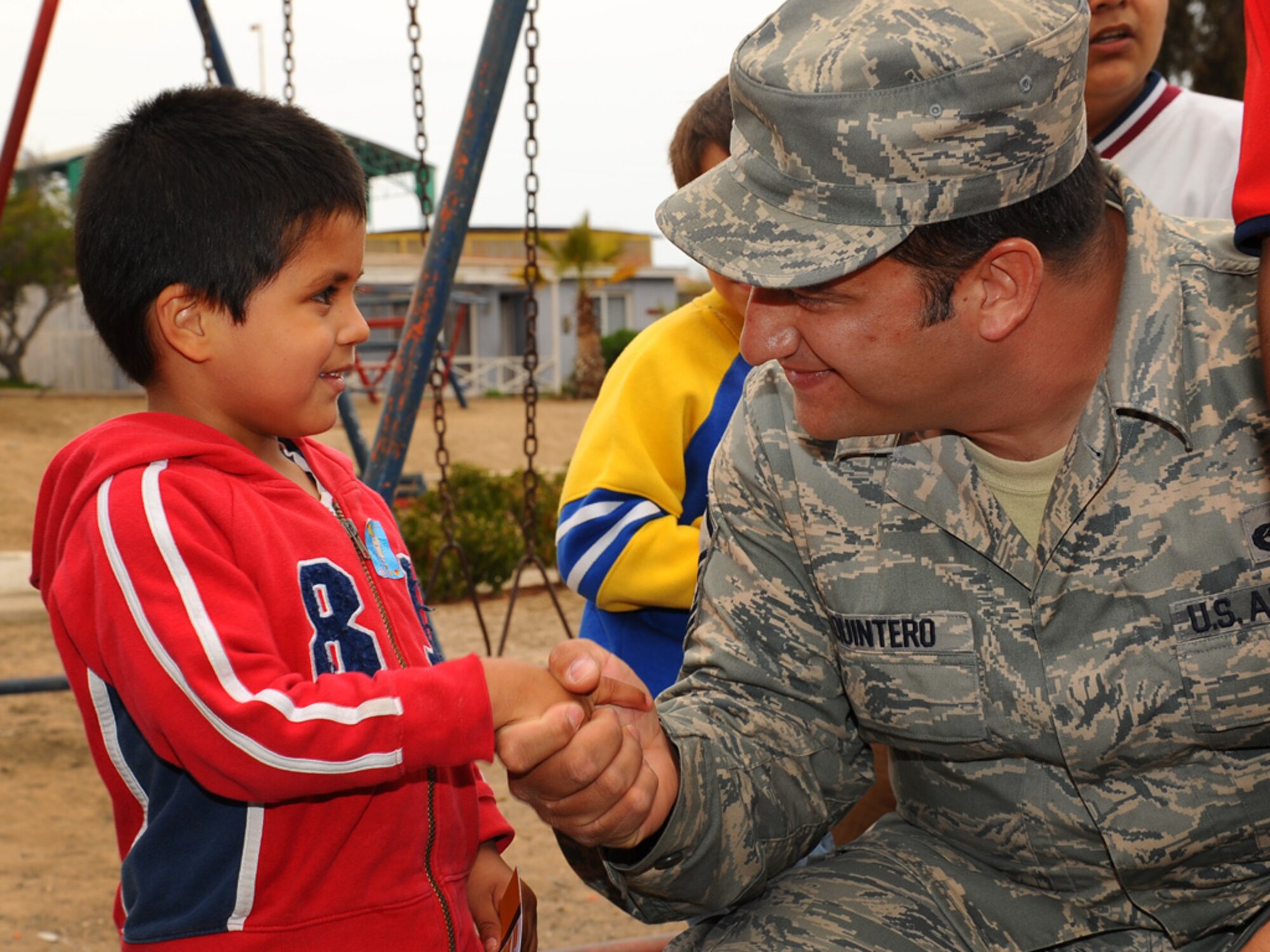 Master Sgt. David Quintero, an aircraft armament systems craftsman, with the 159th Fighter Wing, Louisiana Air National Guard, shakes the hand of child at the Aldeas SOS orphanage in Antofagasta, Chile.  Sergeant Quintero celebrated his own birthday at the center along with more than 40 Airmen from the US, Chilean and Argentine Air Forces who visited the home while taking time off from exercise SALITRE, a five-nation exercise focused on peacekeeping operations.  (U.S. Air Force photo by Master Sgt. Daniel Farrell)