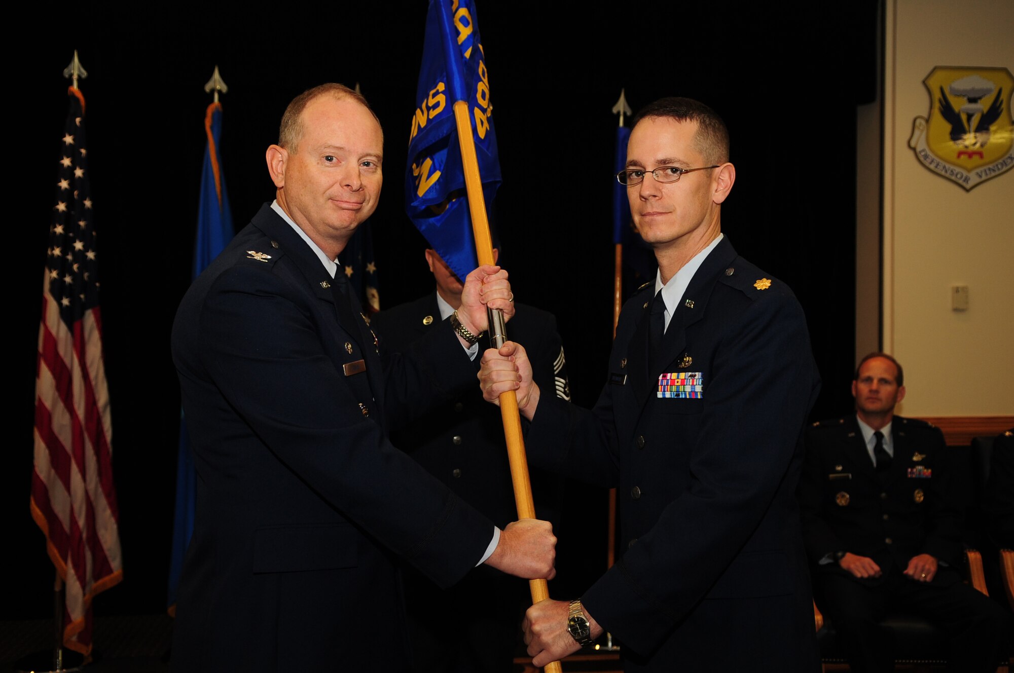 Col. Paul E. Irwin, 498th Munitions Maintenance Group commander (left), Kirtland Air Force Base, N.M., passes the guidon to Maj. George Sherwood, 19th Munitions Squadron commander, Whiteman Air Force Base, Mo., during the 498th Munitions Maintenance Group Relocation of Command ceremony Oct. 25 at Whiteman AFB.  (Air Force photo by Senior Airman Jessica Mae Snow)