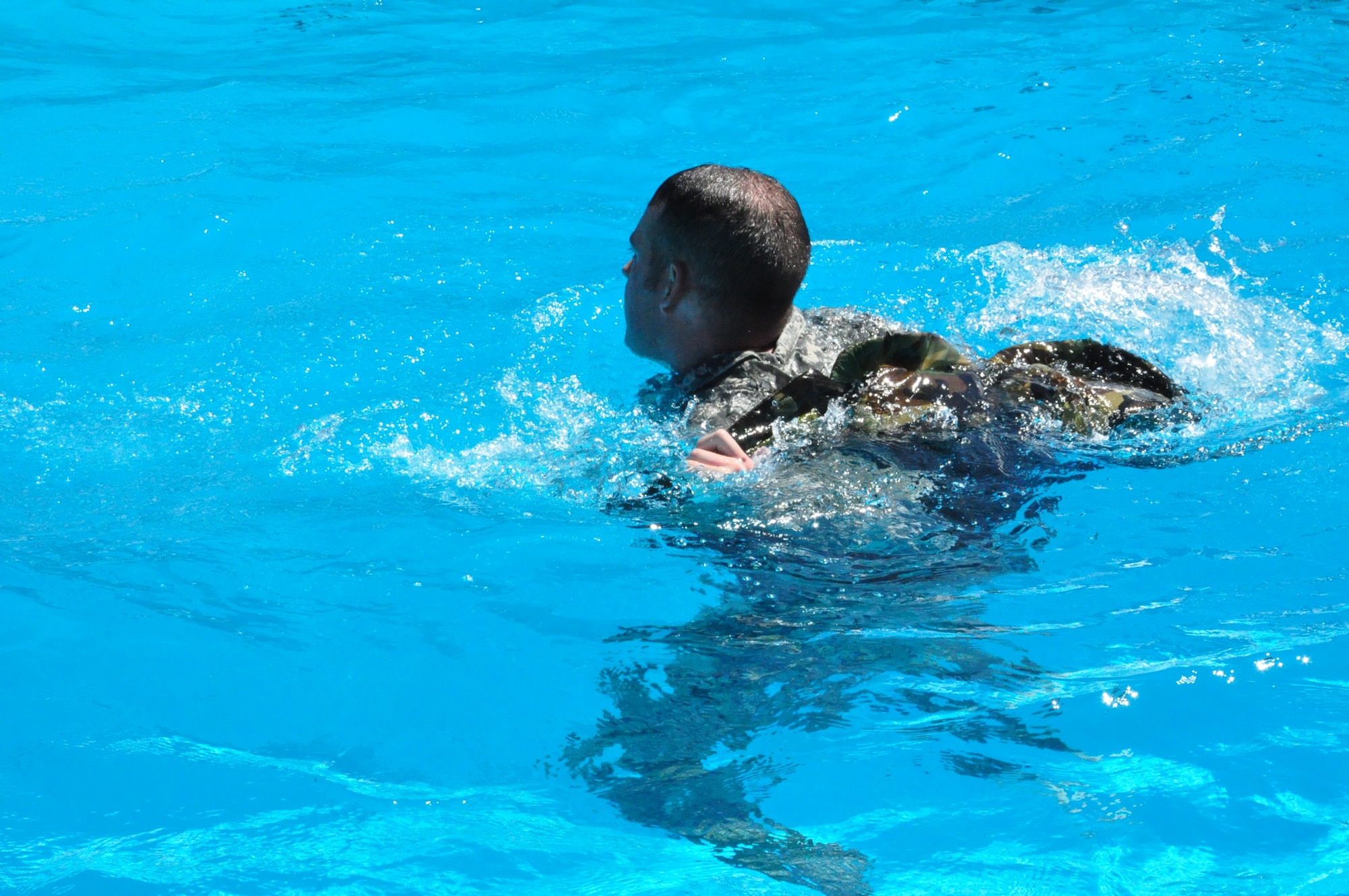 Army Corporal Jason Padgett removes his vest in the water during Water Survival Training at the Soto Cano Air Base swimming pool Thursday, Oct. 22, 2009. Corporal Padgett and 13 other personnel recovery team members trained on a variety of water-based tactics to prepare them to operate safely in rescue and recovery missions. (U.S. Air Force photo/Tech. Sgt. Mike Hammond)