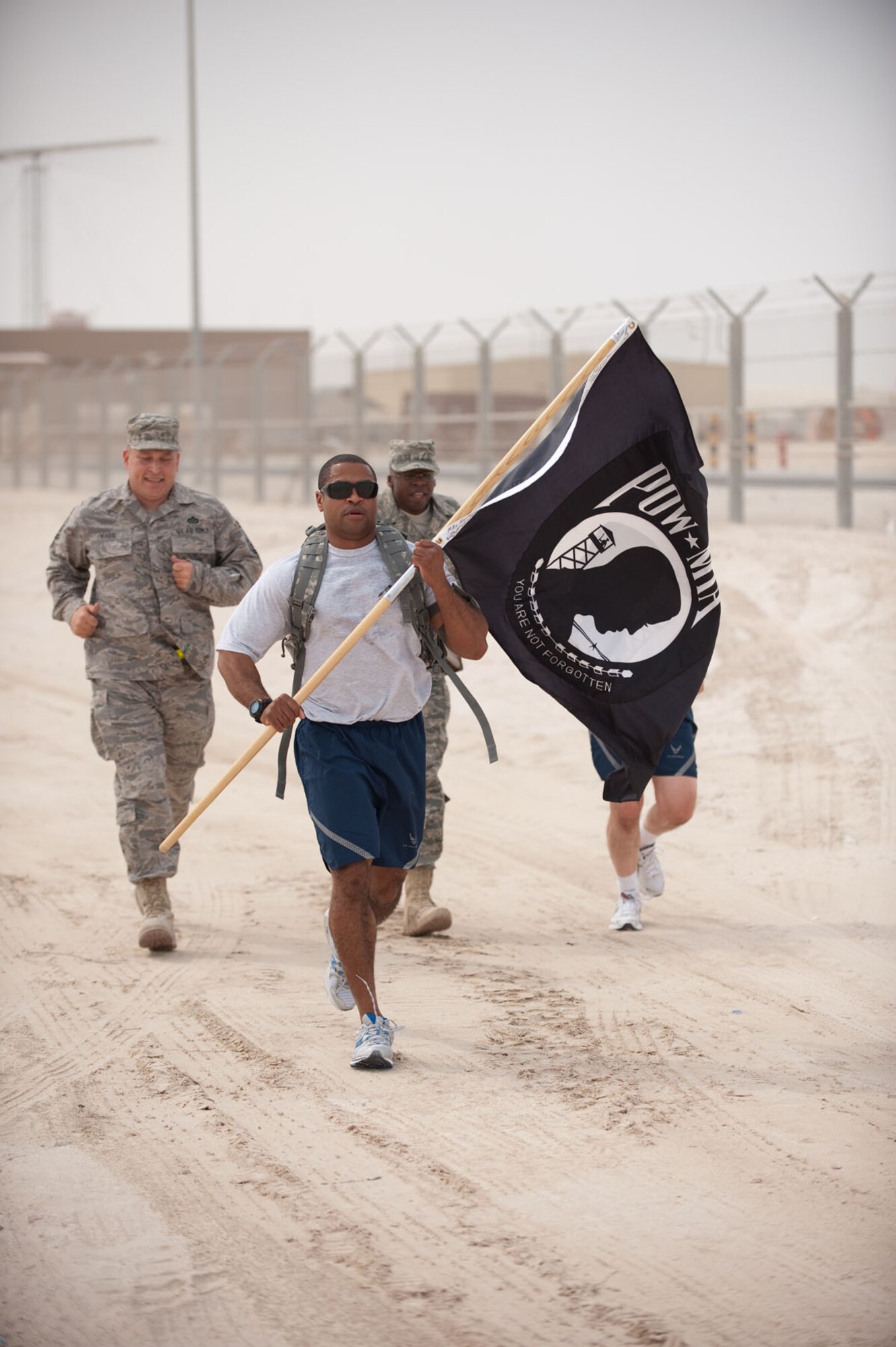 Master Sgt. Gilliuet Owens, 379th Expeditionary Operations Support Squadron, carries the POW/MIA flag with fellow servicemembers as they run a POW/MIA memorial run, Oct. 24, 2009, in Southwest Asia. More than 200 military servicemembers ran, interchangeably, for 24 hours around a half-mile course, continuously carrying the POW/MIA flag to help raise awareness as well as more than $700 for the POW/MIA Combined Federal Campaign charity. (U.S. Air Force photo/Staff Sgt. Robert Barney)