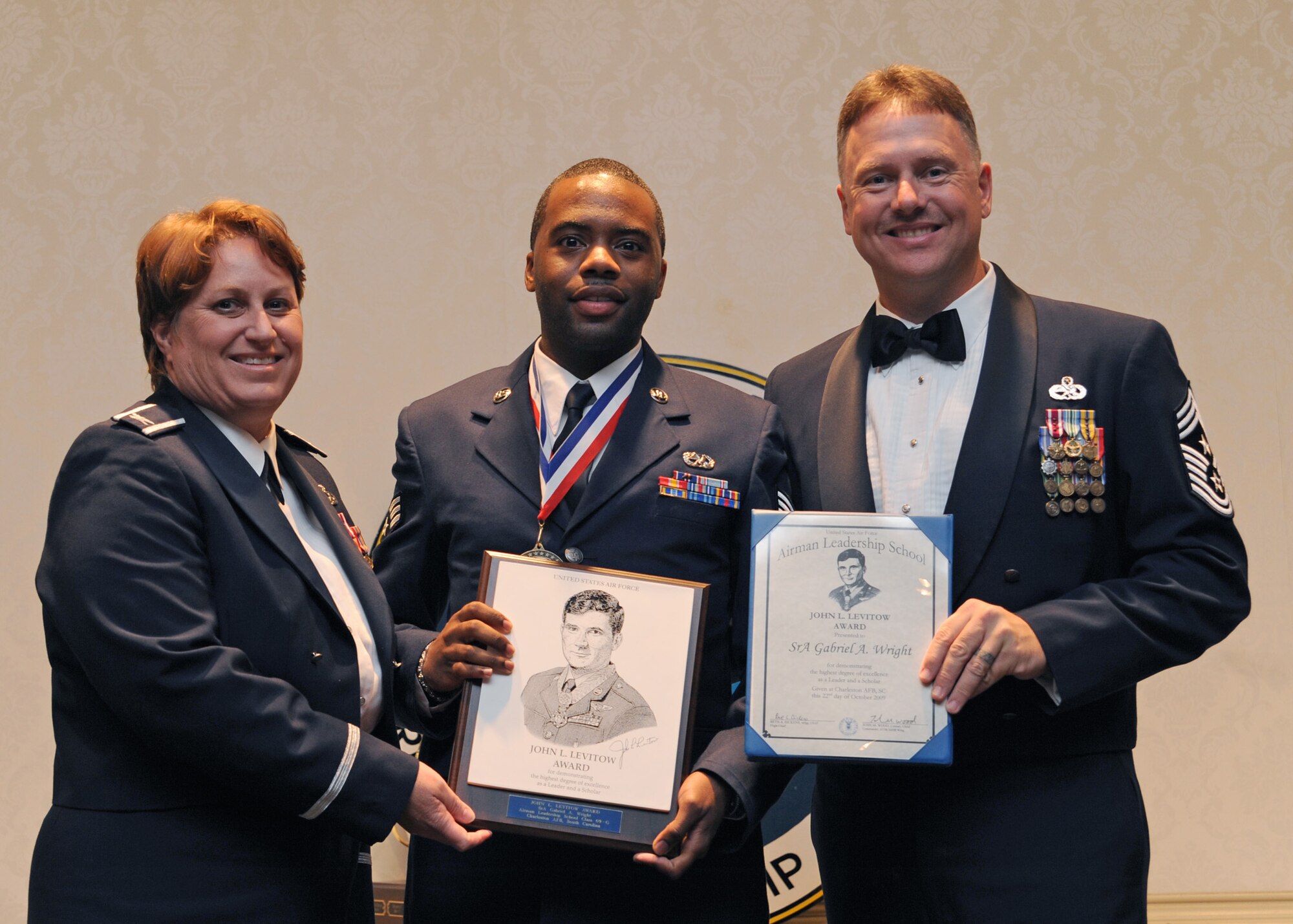 Senior Airman Gabriel Wright receives the John L. Levitow Award at the Charleston Club here during the Airman Leadership School Class 09-G graduation from Col. Tammy Livingood and Chief Master Sgt. Mike Ivey Oct. 22. The John L. Levitow award is the highest award granted in Airman Leadership School. Airman Wright is an electrical and environmental specialist with the 437th Aircraft Maintenance Squadron, Col. Livingood is the 437th Maintenance Group commander and Chief Ivey is the 437th Airlift Wing command chief. (U.S. Air Force photo/Senior Airman Katie Gieratz)
