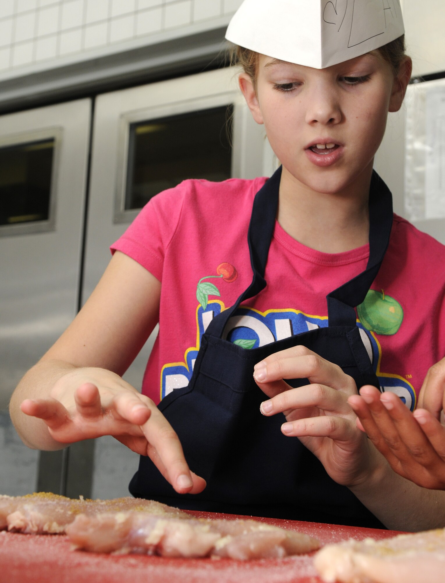 SPANGDAHLEM AIR BASE, Germany – Lanie Moreau, daughter of Tech. Sgt. Jay Moreau, 52nd Civil Engineer Squadron, seasons chicken breast during the Kid’s Iron Chef competition held at the Mosel Dining Facility Oct. 20. Students from the Spangdahlem Middle School were split into three teams, and each team created a different dish to be judged. (U.S. Air Force photo/Airman 1st Class Staci Miller)