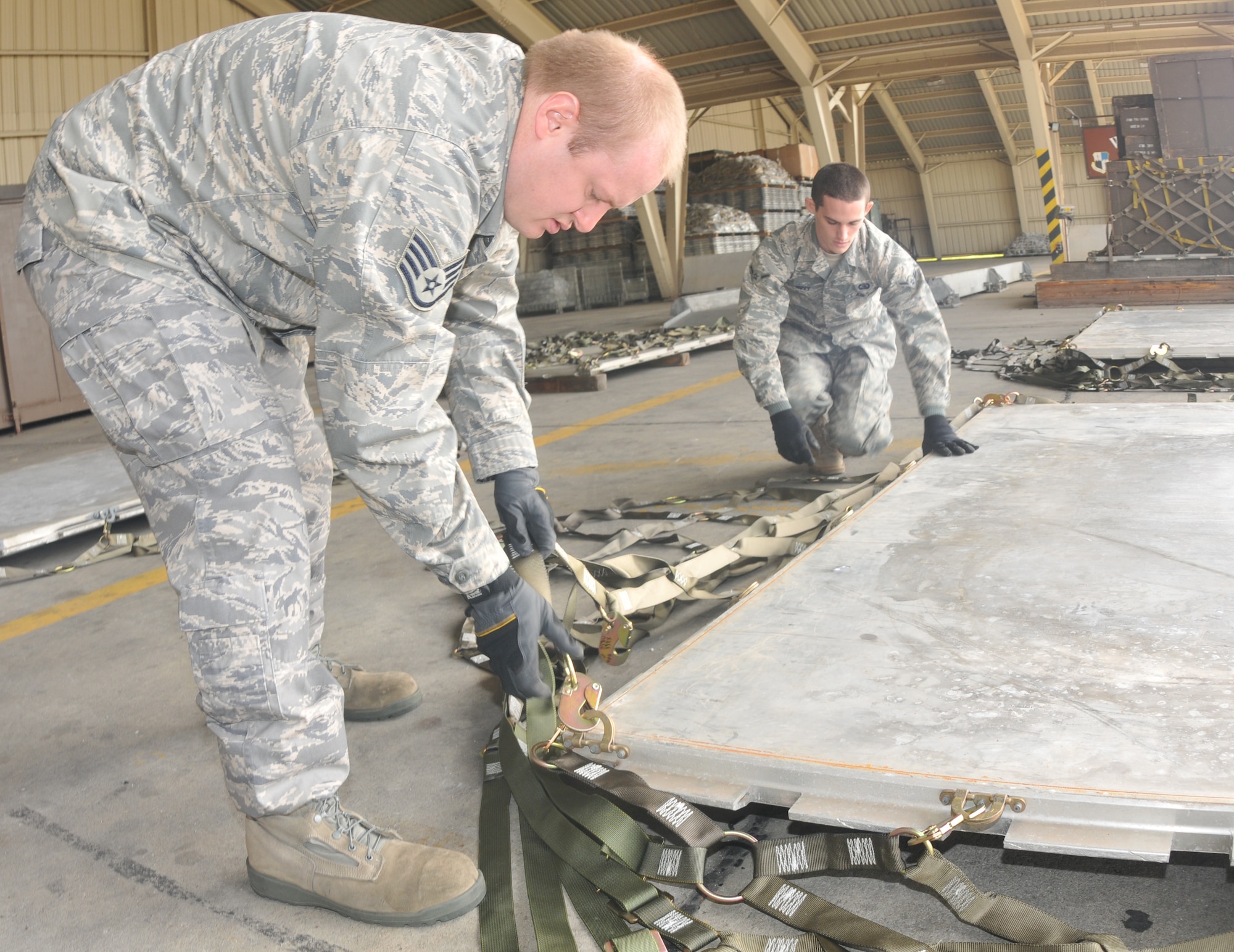 SPANGDAHLEM AIR BASE, Germany -- Staff Sgt. Paul Neyman and Airman Zachary Nuvy, both from the 606th Air Control Squadron, install top net to a cargo pallet during cargo pallet buildup training Oct. 21. The purpose of the class is to give Airmen the skills needed for cargo movement. (U.S. Air Force photo/Airman 1st Class Nick Wilson)
