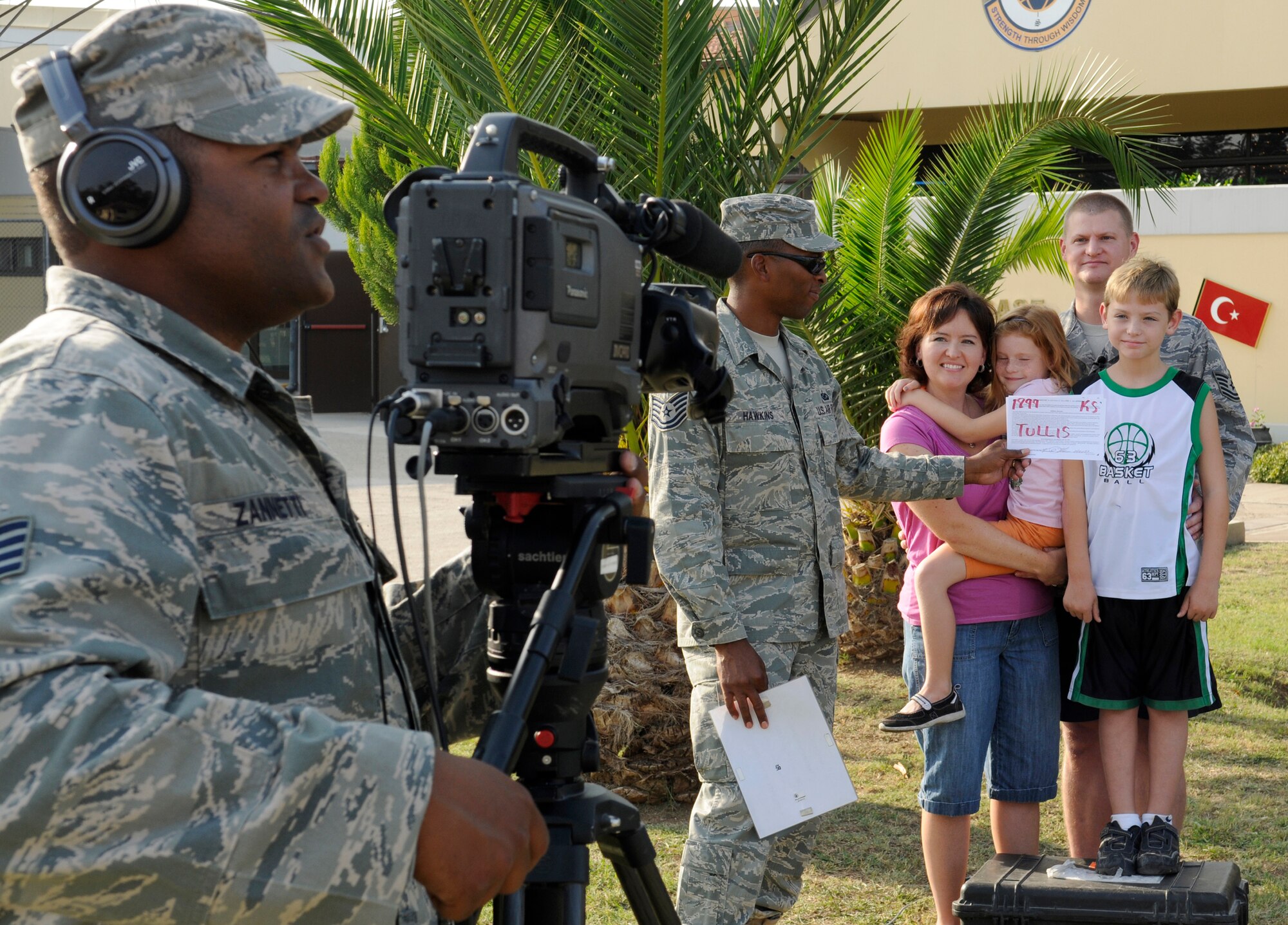 Tech. Sgt. Kent Tullis, 39th Medical Operations Squadron, stands with his family, (left to right) Dayna, Olivia and Isaac, as they record a season’s greetings Saturday, Oct. 24, 2009 in front of the 728th Air Mobility Squadron’s passenger terminal.  The greetings will be taken back to the U.S. and sent out to the individual’s hometown news agencies to be played during commercial breaks between Thanksgiving and New Years.  Incirlik families, along with families at geographically separated units around Turkey, filmed more than 230 season’s greetings.  (U.S. Air Force photo/Staff Sgt. Raymond Hoy)