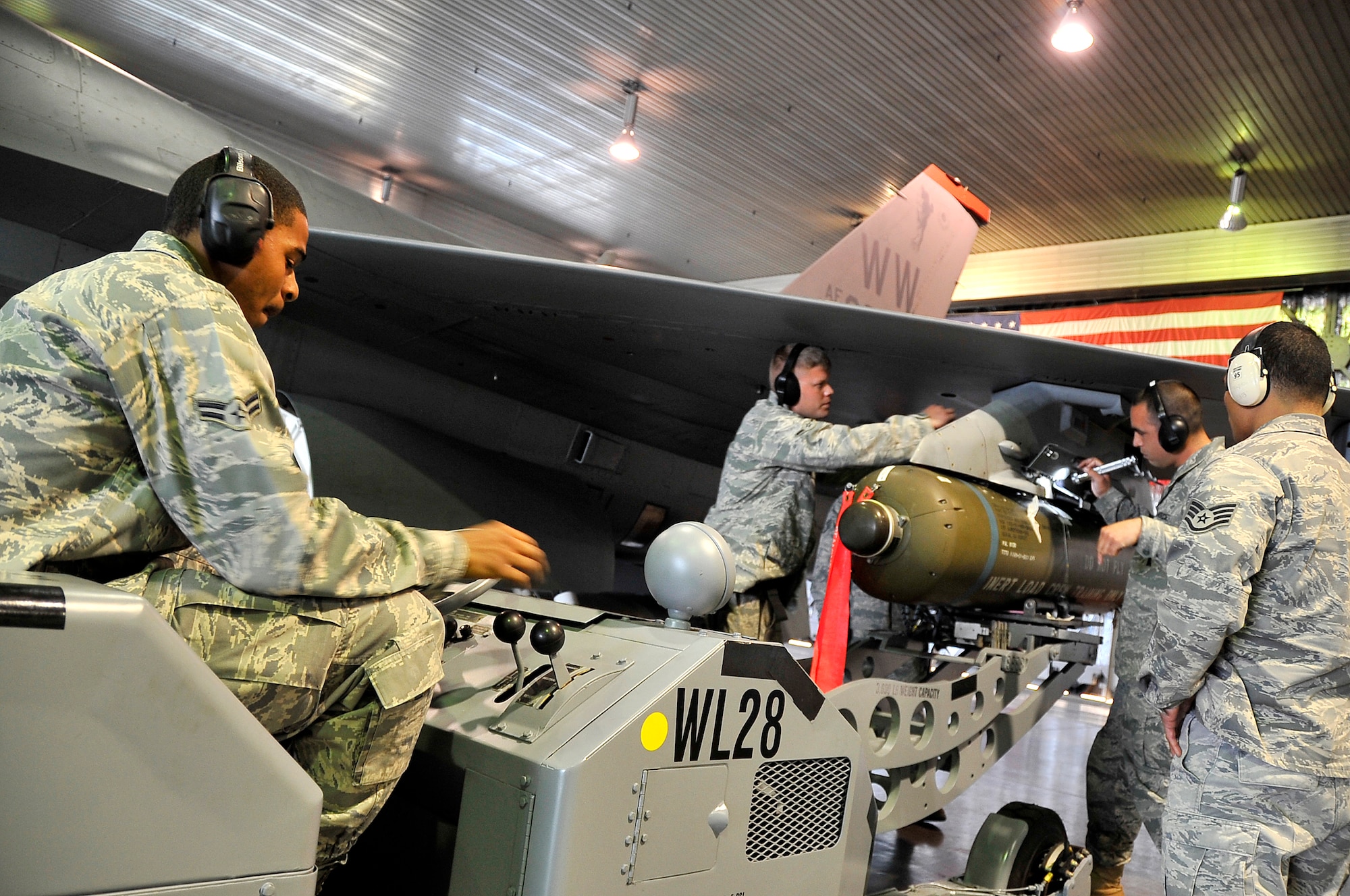 MISAWA AIR BASE, Japan -- Airman 1st Class Mathew Henderson and Airman Daniel Nikula, 13th Aircraft Maintenance Unit weapons specialists, assist their team in loading a cluster bomb onto an F-16 Fighting Falcon with an MJ-1 lift truck during the weapons load crew competition Oct. 23. The MJ-1, also called a "jammer," is used to load and unload a wide variety of munitions and has a lifting capacity of 3,000 pounds. (U.S. Air Force photo/Staff Sgt. Chad C. Strohmeyer).