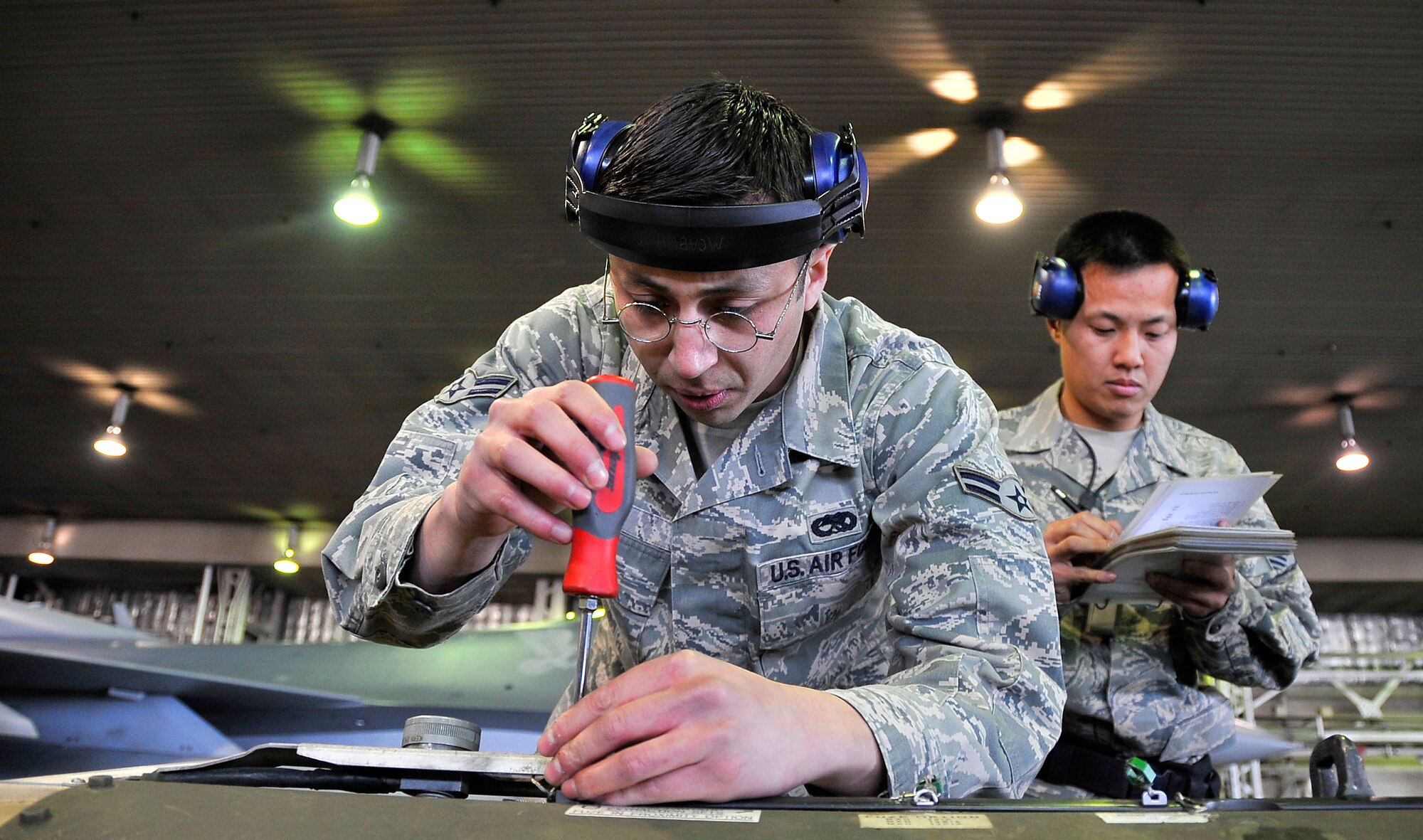 MISAWA AIR BASE, Japan -- Airman 1st Class Noe Leon and Staff Sgt. David Hsu, 14th Aircraft Maintenance Unit weapons specialists, ensure the screws are seated in a conduit on a cluster bomb during the weapons load crew competition Oct. 23. Airman Leon's job was to prepare the munitions before being loaded onto the aircraft. (U.S. Air Force photo/Staff Sgt. Chad C. Strohmeyer).