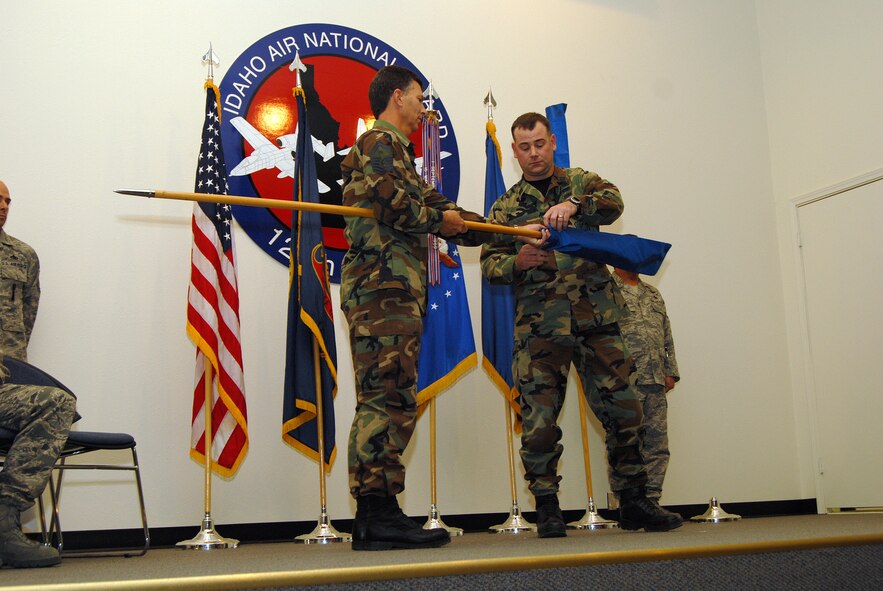 Capt. Craig Wood, 124th Aerial Port Flight commander, Idaho Air National Guard, encases the unit flag for the final time symbolizing the official deactivation of the unit. Holding the staff is Senior Master Sgt. (Ret.) Russell Heltzel, former first sergeant for the aerial port. From 1996 to 2009, the unit provided cargo and passenger support in Idaho and around the world to Air Mobility Command assets. One member of the Aerial Port Flight remains deployed in support of operations in the area of responsibility. (Air Force photo by Staff Sgt Heather Walsh)(Released)