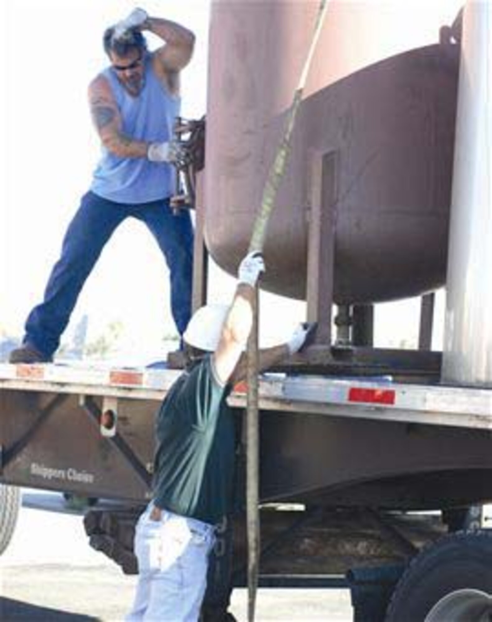 Contractors guide a crane-lifted tank onto a truck bed Sept. 22, 2009, at March Air Reserve Base, Calif. The tank was part of the ground water and soil vapor extraction system that was installed on base in 1997. After cleaning an equivalent of 58,000 gallons of jet fuel, the system is no longer needed. (U.S. Air Force photo/Staff Sgt. Megan Crusher)