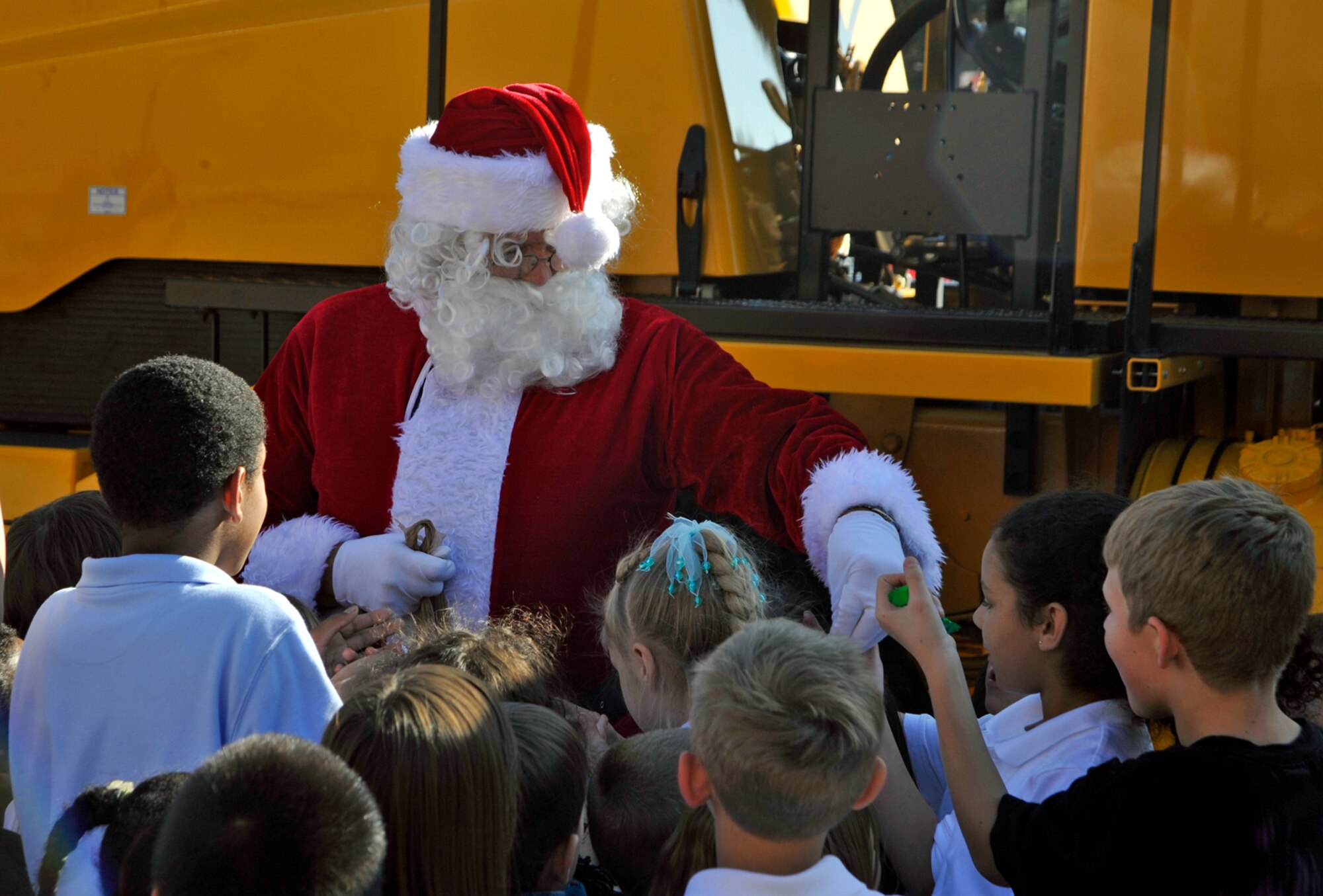 PETERSON AIR FORCE BASE, Colo. -- Larry Eller, 21st Civil Engineer Squadron, dressed as Santa Clause, gives candy to children at the R.P. Lee Youth Center after the annual base snow parade at Peterson Oct. 23. Members of the 21st CES, accompanied by 21st Space Wing leadership and Santa Clause, drove snow plows, dump trucks, fire trucks and other winter equipment through the base to show the vehicles to base personnel. (Air Force photo)