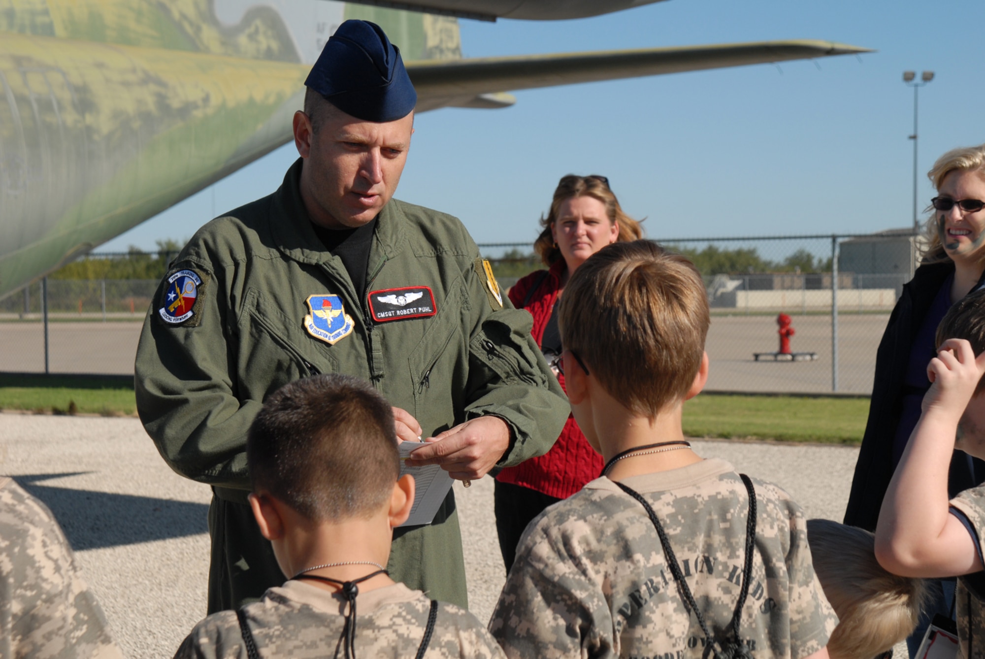 GOODFELLOW AIR FORCE BASE, Texas -- Chief Master Sgt. Robert Puhl, 17th Training Group chief enlisted manager, checks identification cards before kids board a C-130 during Operation Kids, Oct. 24, 2009. Operation Kids is a group of activities designed to increase dependents' understanding of the deployment process. (U.S. Air Force photo/Staff Sgt. Laura R. McFarlane)