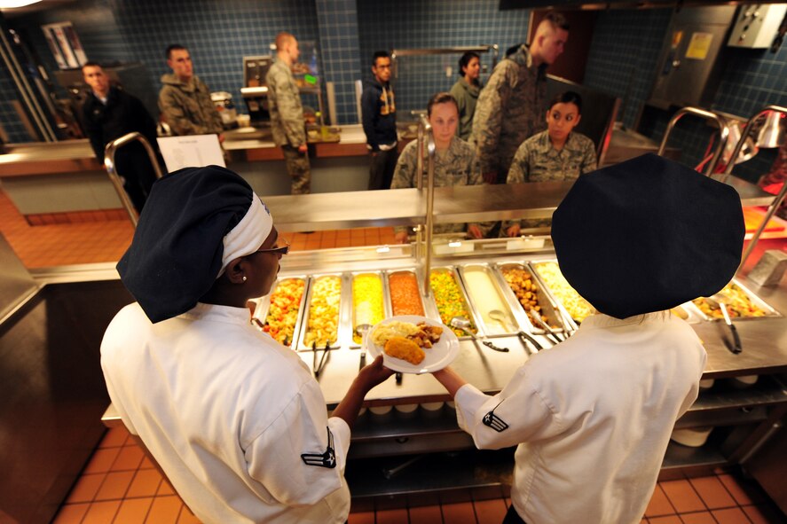 OFFUTT AIR FORCE BASE, Neb. - Airman 1st Class Sasha Farmer (left) and Senior Airman Rachael Price (right), both with the 55th Force Support Squadron, serve Airmen lunch at the Ronald L. King Dining Facility here Oct. 22.  The King Dining Facility serves more than 17,000 meals a month providing food for Offutt's warriors. Air Combat Command's Hennessy Inspection Team visits Offutt Nov. 1 - 4 to evaluate the King Dining Facility and the Campsisi Dining Facility as they compete for the prestigious Hennessy Award, an honor that recognizes the best Dining Facility Program in the Air Force. U.S. Air Force Photo by Josh Plueger