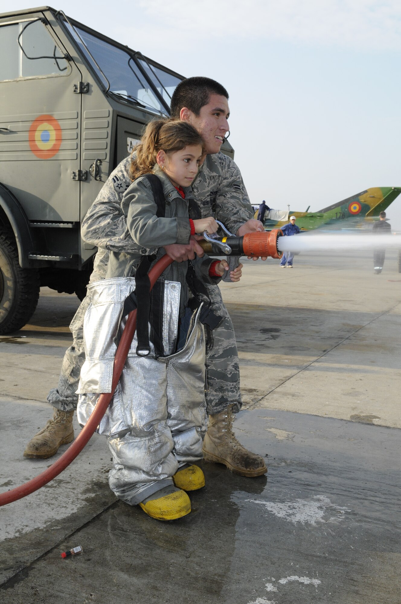 CAMPIA TURZII, Romania – Airman 1st Class Anthony Alvarez, 52nd Civil Engineer Squadron, helps a Romanian girl spray a fire hose during her visit to the 71st Air Base Wing Oct. 26. Members of Spangdalem Air Base deployed in support of Operation Dacian Thunder 2009 explained the parts of an A-10 Thunderbolt II static display  and a fire truck to children from the town of Turda, Romania, during their visit. The deployed units also donated money and time to help renovate a community center dedicated to helping local children with their academic studies. (U.S. Air Force photo/Senior Airman Benjamin Wilson)