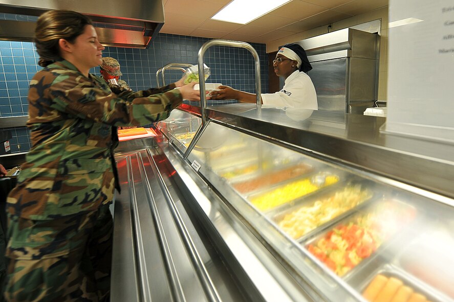 OFFUTT AIR FORCE BASE, Neb., -- Senior Airman Sasha Farmer, 55th Force Support Squadron, hands Airman 1st Class Spencer Delling, 338th  Combat Training Squadron, a plate of food during the lunch service at the Ronald L. King Dining Facility here Oct. 22. The King Dining Facility serves more than 17,000 meals a month providing food for Offutt's warriors. Air Combat Command's Hennessy Inspection Team visits Offutt Nov. 1 - 4 to evaluate the King Dining Facility and the Campsisi Dining Facility as they compete for the prestigious Hennessy Award, an honor that recognizes the best Dining Facility Program in the Air Force. U.S. Air Force Photo by Charles Haymond