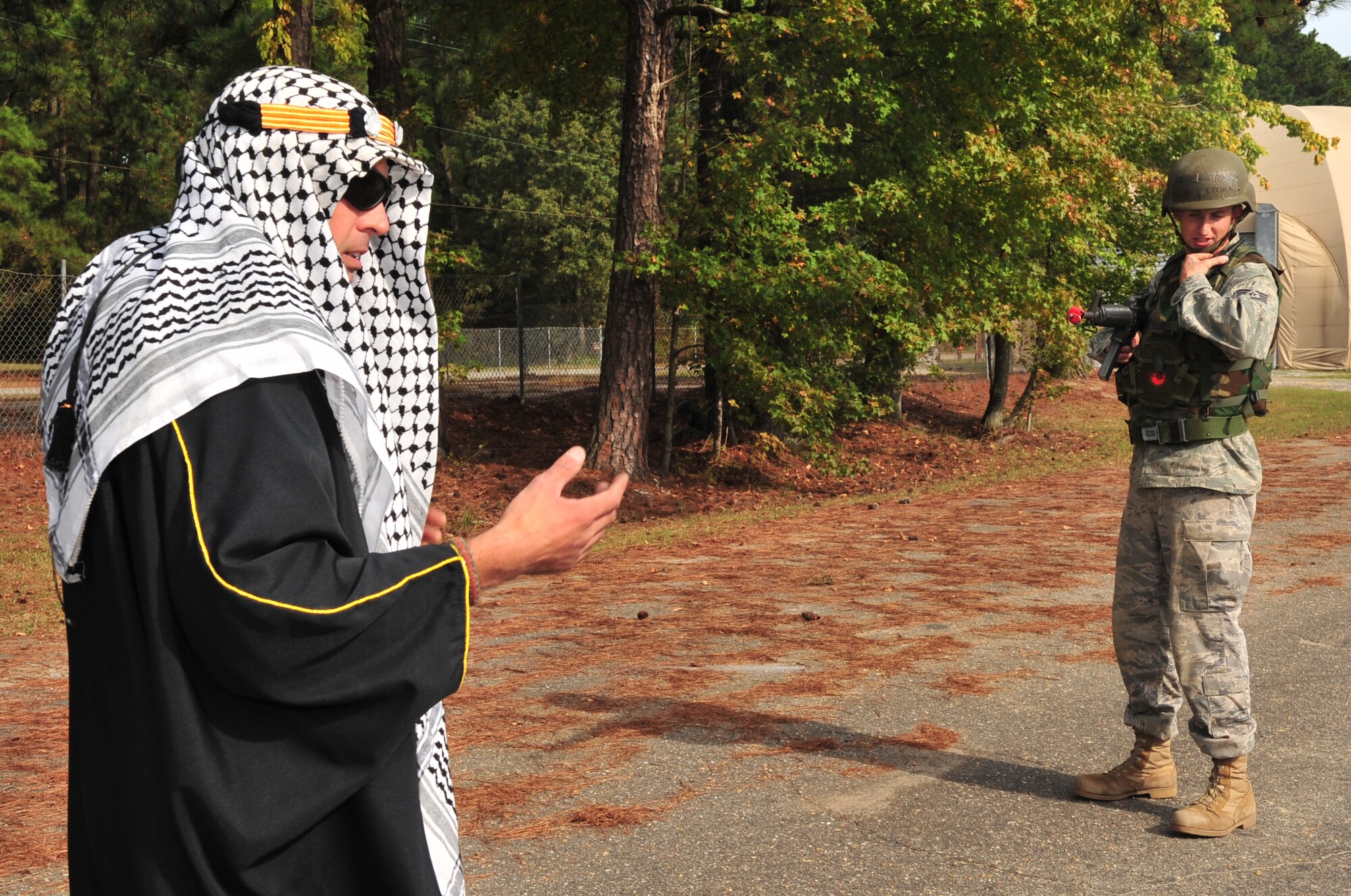 Staff Sgt. Anthony Fletcher, 4th Civil Engineer Squadron utilities systems journeyman, radios to his commander while keeping an eye on the simulated Afghani tribal chief during expeditionary combat skills training at Seymour Johnson Air Force Base, N.C., Oct. 22, 2009. Training scenarios teach Airmen about different cultures and the use of the rules of engagement in deployed locations. (U.S. Air Force photo/Airman 1st Class Rae Perry)