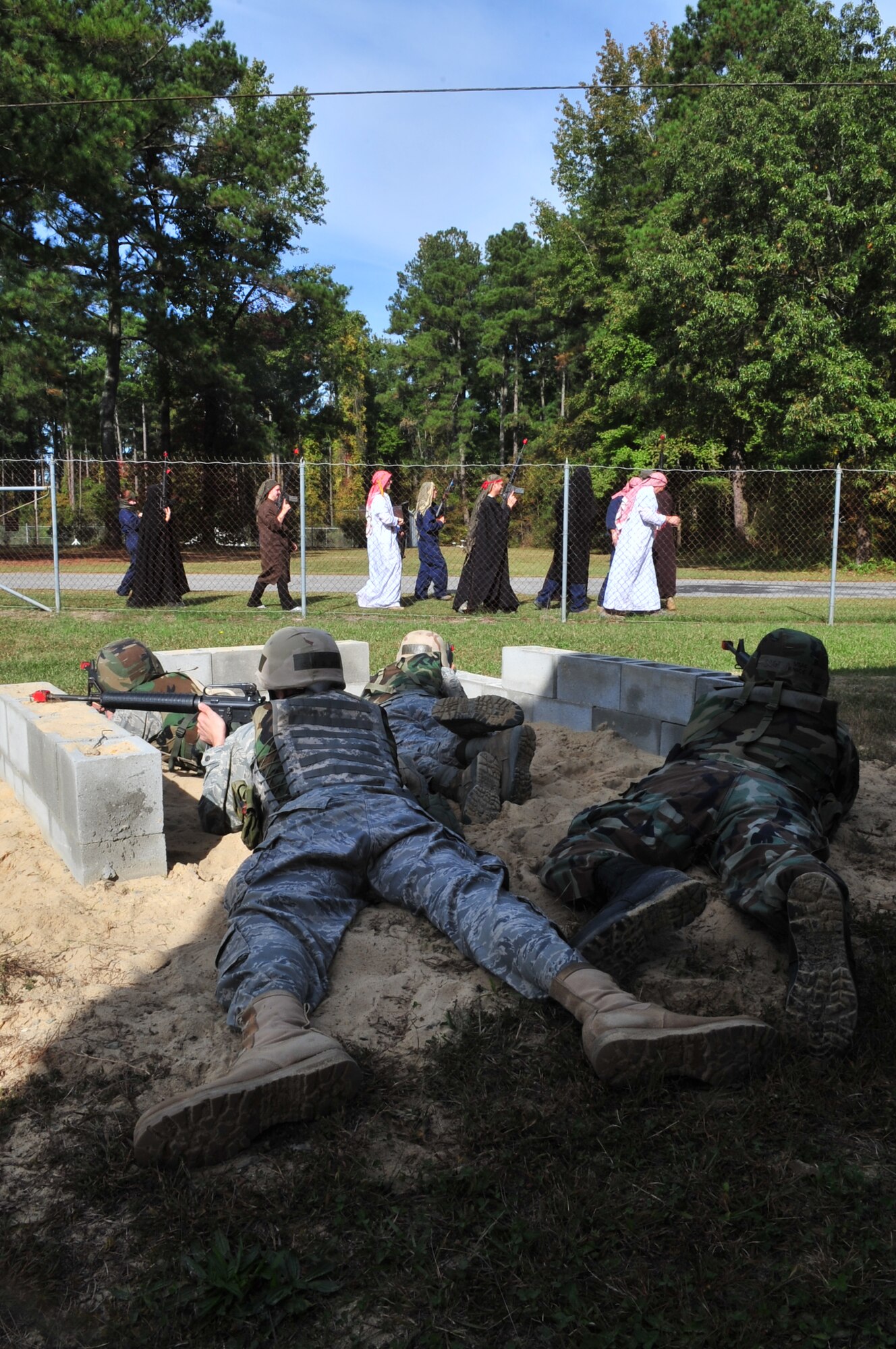 Four Airman watch as a group of simulated foreign nationals walk past the base fence line during a field training exercise at Seymour Johnson Air Force Base, N.C., Oct. 22, 2009. All Airmen who deploy complete the three-day expeditionary combat skills training prior to deployment. (U.S. Air Force photo/Airman 1st Class Rae Perry)