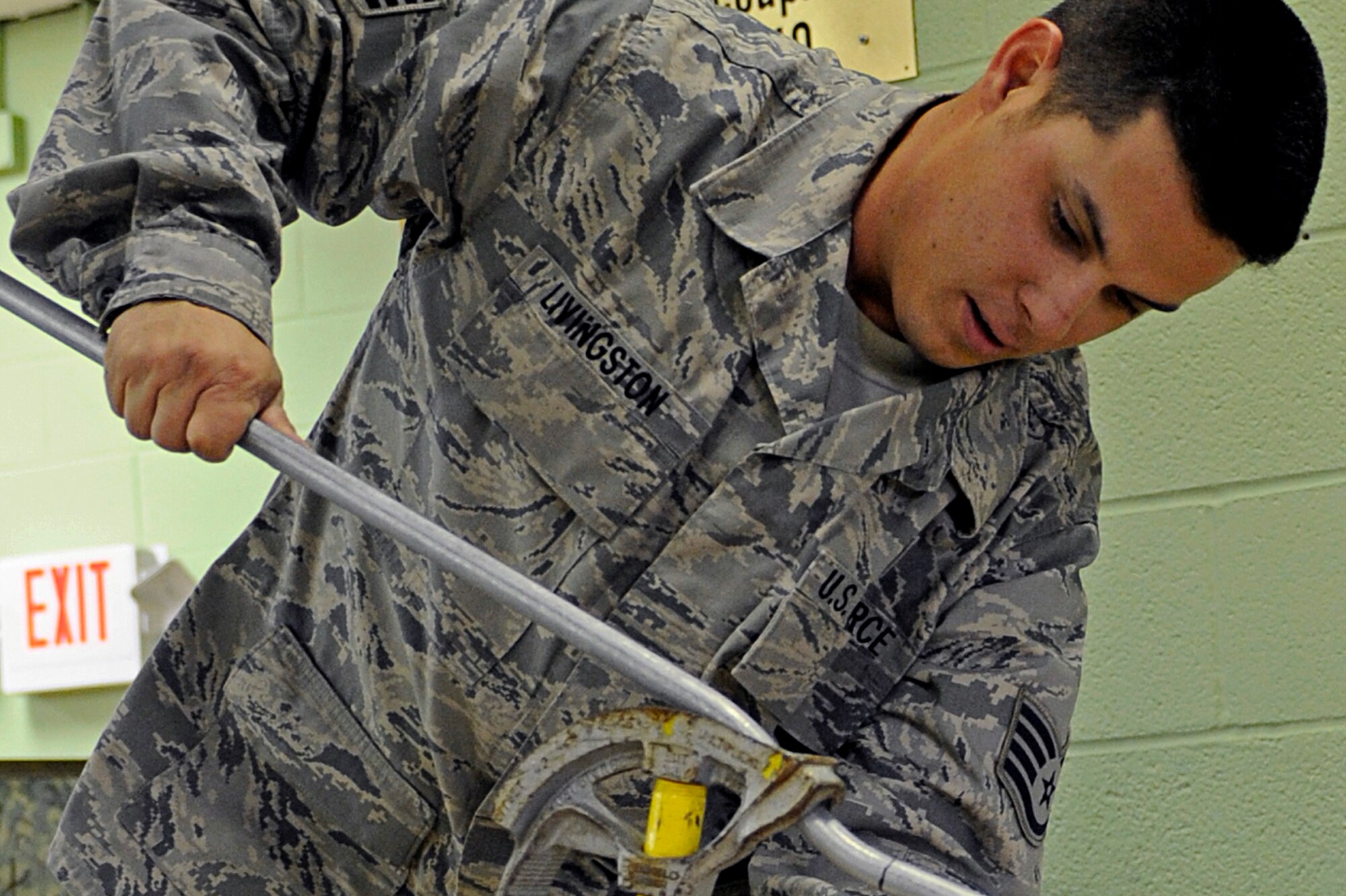 Staff Sgt. James Livingston, 28th Civil Engineer Squadron electrical systems technician, bends a pipe here, Oct. 22. Sergeant Livingston bends the pipe to make a conduit run power to a back room at the youth center. (U.S. Air Force photo/Airman 1st Class Matthew Flynn)