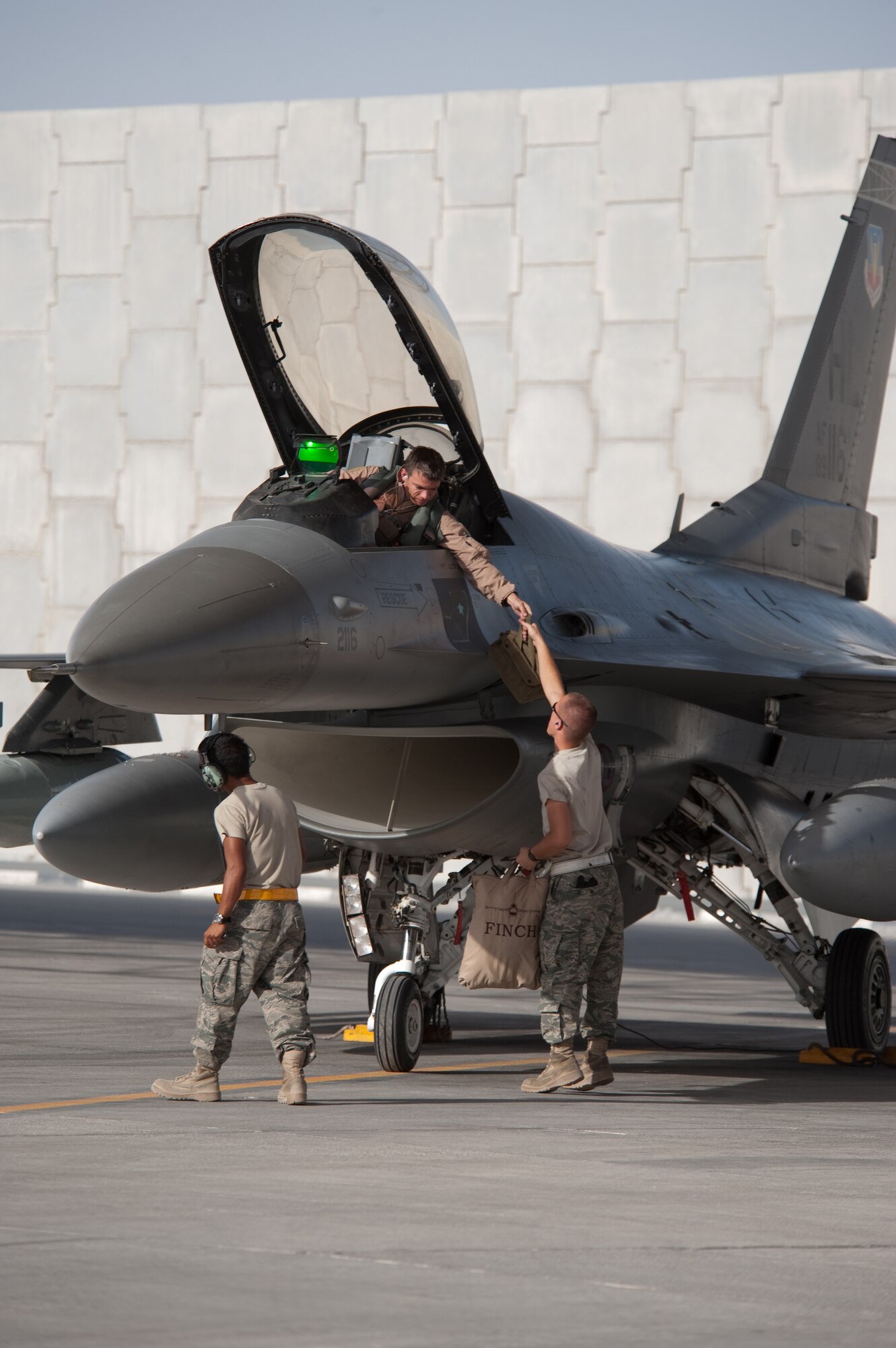 U.S. Air Force Capt. David Guenthner hands his gear to Airman 1st Class Ted Schaefer after landing in Southwest Asia, Oct. 13, 2009. The 379th Air Expeditionary Wing is temporarily hosted the F-16s from the 421st Fighter Squadron at Hill Air Force Base, Utah, in support of operation Enduring Freedom. (U.S. Air Force photo/Staff Sgt. Robert Barney/RELEASED) 