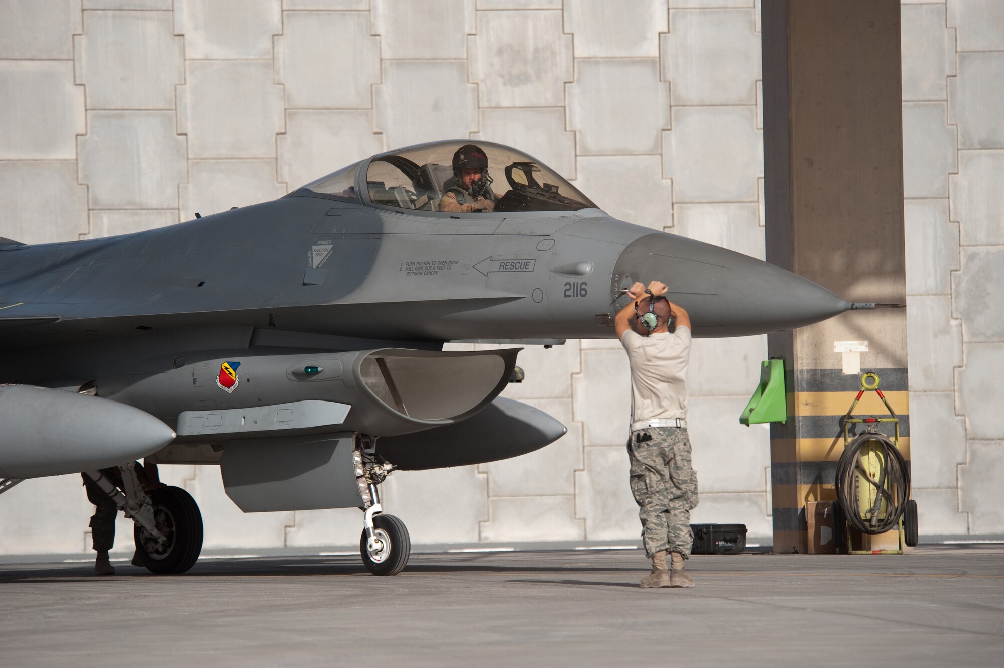 Left, U.S. Air Force Airman 1st Class Ted Schaefer, 421st Expeditionary Fighter Squadron crew chief, marshals an F-16 Fighting Falcon to a stop, Oct. 13, 2009, in Southwest Asia. The 379th Air Expeditionary Wing is temporarily hosting the F-16s during the squadron's deployment from Hill Air Force Base, Utah, in support of operation Enduring Freedom. (U.S. Air Force photo/Staff Sgt. Robert Barney/RELEASED) 