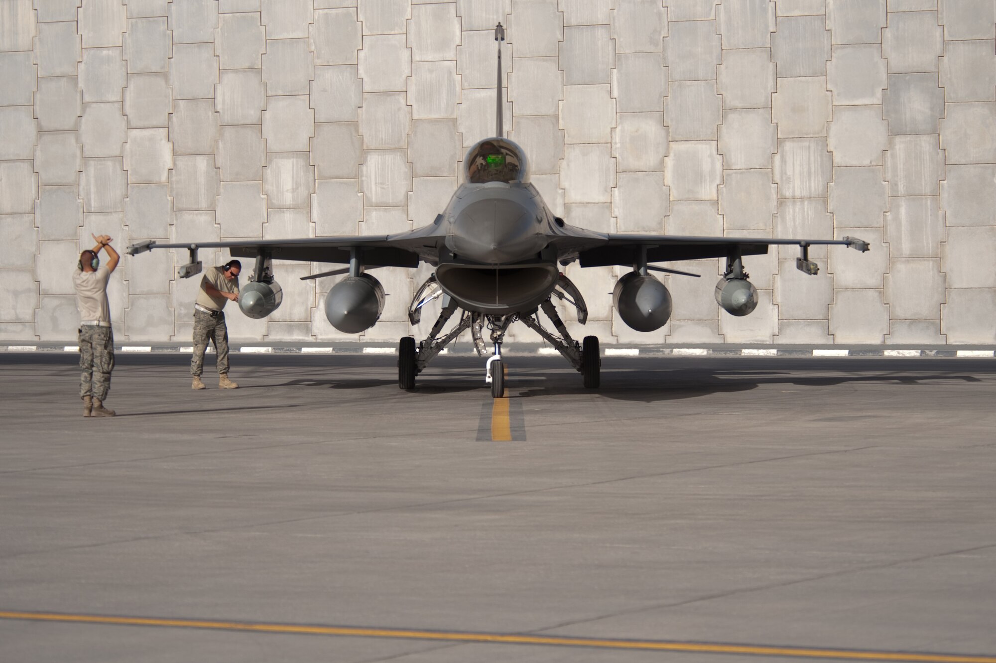 Left, U.S. Air Force Airman 1st Class Ted Schaefer, 421st Expeditionary Fighter Squadron crew chief, marshals an F-16 Fighting Falcon to a stop, Oct. 13, 2009, in Southwest Asia. The 379th Air Expeditionary Wing is temporarily hosting the F-16s during the squadron's deployment from Hill Air Force Base, Utah, in support of operation Enduring Freedom. (U.S. Air Force photo/Staff Sgt. Robert Barney/RELEASED) 