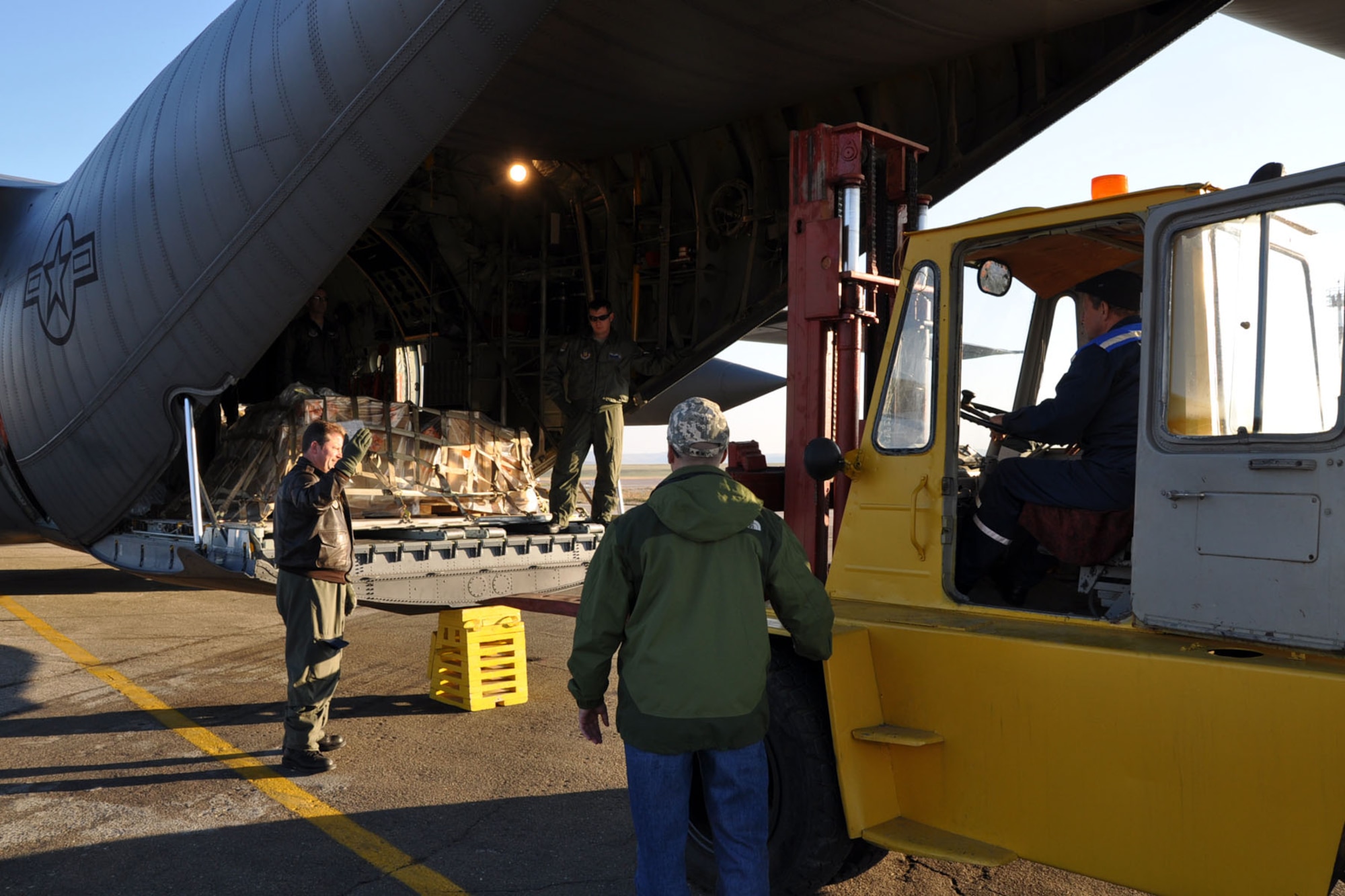 CHISINAU, Moldova -- Air Force Reserve Master Sgt. Mark Zickefoose directs a forklift towards the cargo ramp of a C-130H Hercules tactical cargo transport aircraft, asssigned to the 910th Airlift Wing based at Youngstown Air Reserve Station, Ohio, at the airport here, October 22, 2009. Navigator Lt. Col. Don Loomis (behind cargo pallet) and loadmaster Sr. Airman Brent Bate watch from the interior of the C-130's cargo deck as the forklift approaches the aircraft to unload cargo. These Citizen Airmen and five others from YARS are on an airlift mission delivering passengers and supplies to Chisinau, the capital city of Moldova, located in eastern Europe between Romania and the Ukraine. The aircrew members on this flight are among more than 70 Servicemembers from the 910th AW attached to the 38th Expeditionary Airlift Squadron, based here. The 38th EAS is supporting Operation Joint Enterprise by providing tactical airlift capability to locations in the U.S. Europe Command (EUROCOM), U.S. Africa Command (AFRICOM) and U.S. Central Command (CENTCOM) theaters of operations. U.S. Air Force photo by Master Sgt. Bob Barko Jr.
