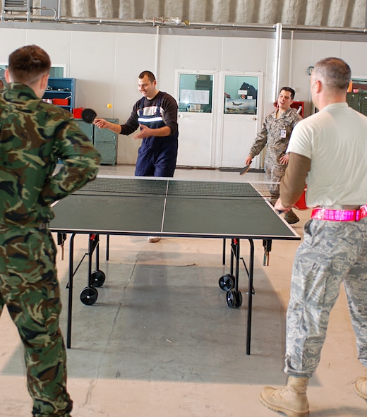 CAMPIA-TURZII, Romania -- Airmen from the 52nd Fighter Wing play pingpong with members of he Romanian air force in a shared hangar here. About 250 52nd FW Airmen and five A-10 Thunderbolt IIs are part of Dacian Thunder, a month-long combined training exercise focused on combat search and rescue, air-to-air and air-to-ground, and weapons delivery missions. During their spare time, Romanian and American Airmen challenged each other to matches on the pingpong table, which stood between the 52nd Fighter Wing’s designated maintenance area and Romanian air force's MiG-21 maintenance area. (U.S. Air Force photo/2nd Lt. Kathleen Polesnak)