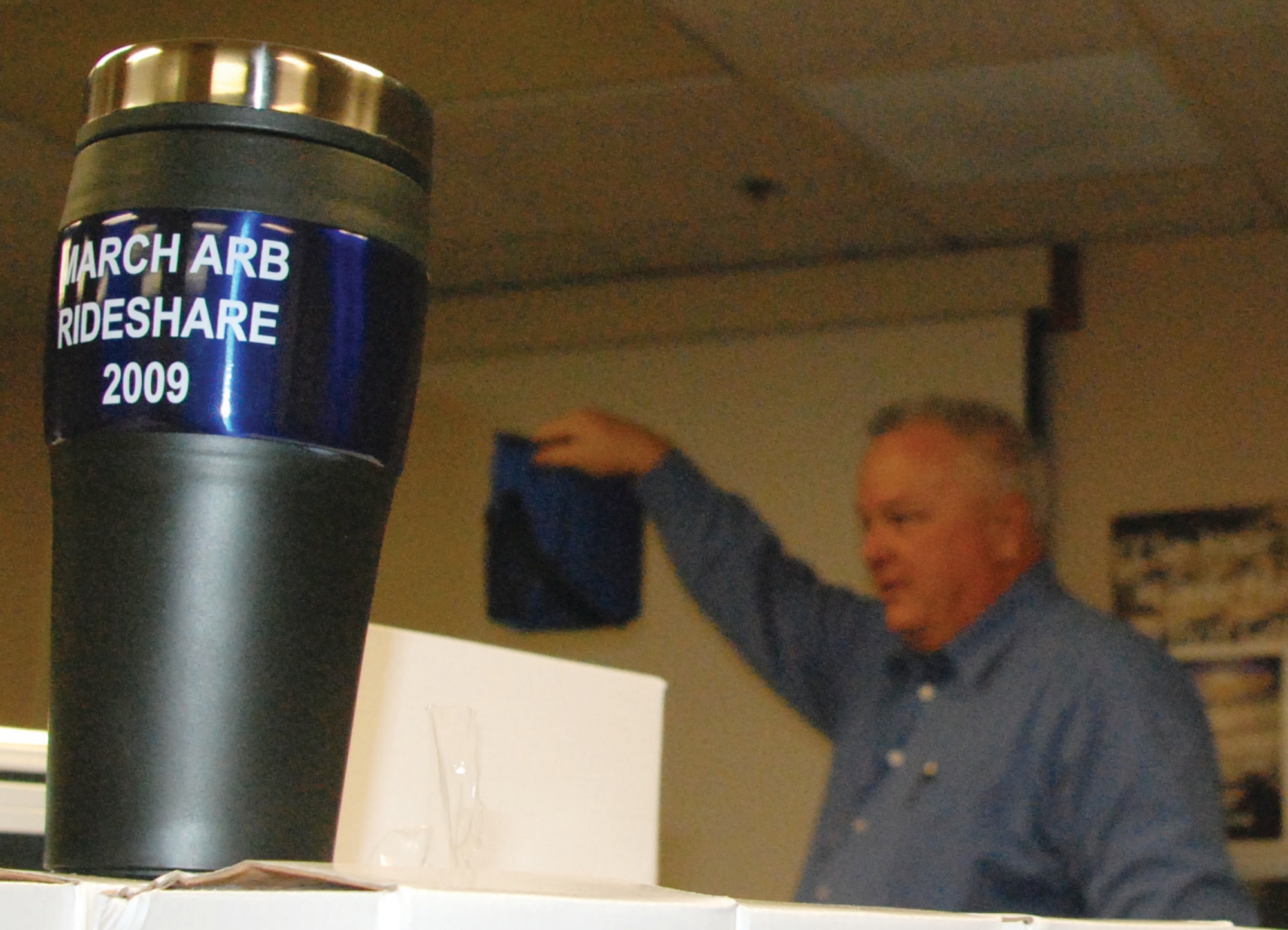 WHO WANTS A LUNCH BAG? March ARB Rideshare Coordinator, Mr. Paul Pitman displays a reusable lunch bag with a Rideshare logo to a Team March member gathered at the SSI conference room Tuesday.  Each Rideshare participant received a stainless steel travel mug for using environmentally-conscious transportation at least once during the week of Oct. 5-9. Pitman also gave away Rideshare paraphernalia such as pens and lip balm.  Pitman expects to  hear the results of the drawing for the advertised gift certificates by the end of the week. (U.S. Air Force Photo by Megan Just)