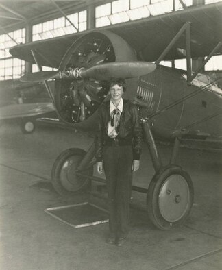 Amelia Earhart stands in front of a Boeing P-12 in a March Field hangar.