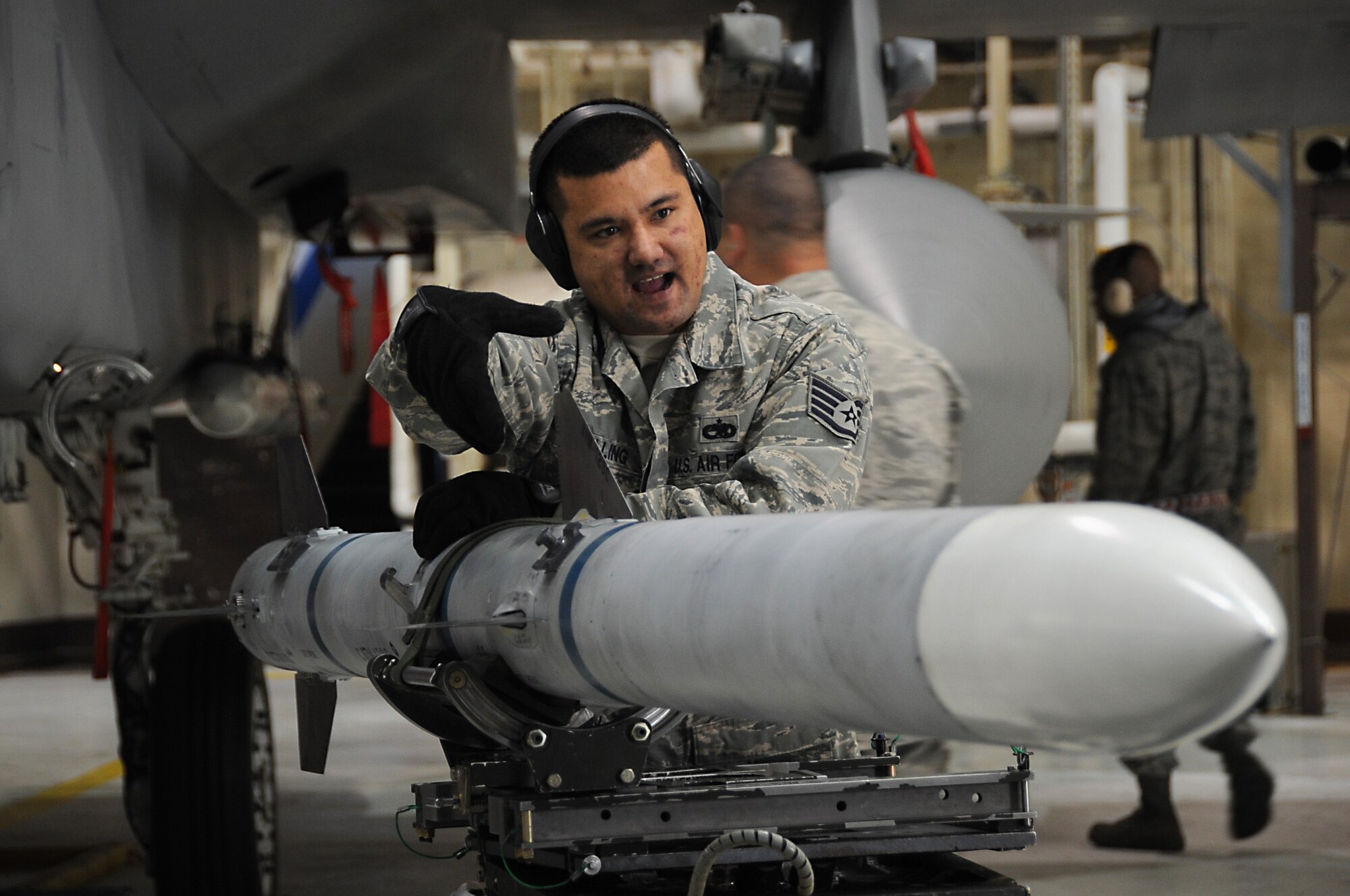 ELMENDORF AIR FORCE BASE, Alaska -- Staff Sgt. Leon Schilling directs a crew member to lower an air intercept missile 120 on the bomb lift Oct. 20. An AIM 120 weights 335 pounds and is 12 feet long, therefore the use of the bomb lift is needed for loading and unloading. Schilling is an aircraft armament systems specialist with the 19th Aircraft Maintenance Unit. (U.S. Air Force photo/Senior Airman Cynthia Spalding) 