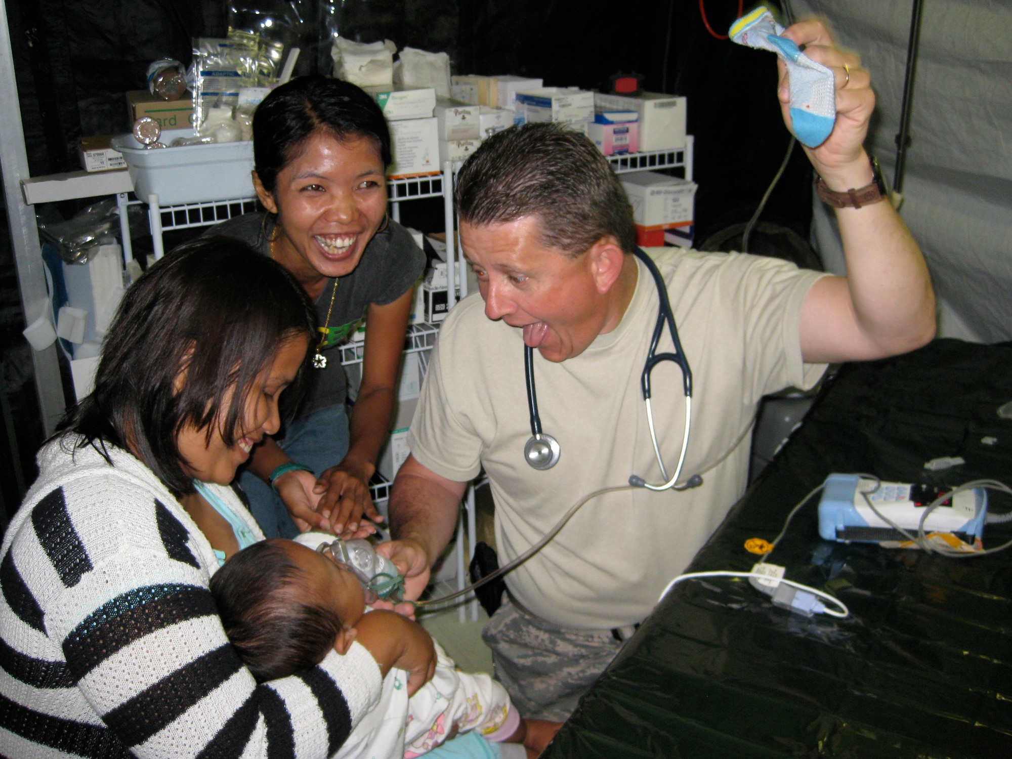 PADANG, Indonesia -- Master Sgt. William Lallish, 3rd Medical Group flight chief, entertains a child while he monitors breathing during treatment. Lallish was a member of the Humanitarian Assistance Rapid Response Team, or HARRT, who were helping in Indonesia after the Sept. 30 earthquake.(courtesy photo)