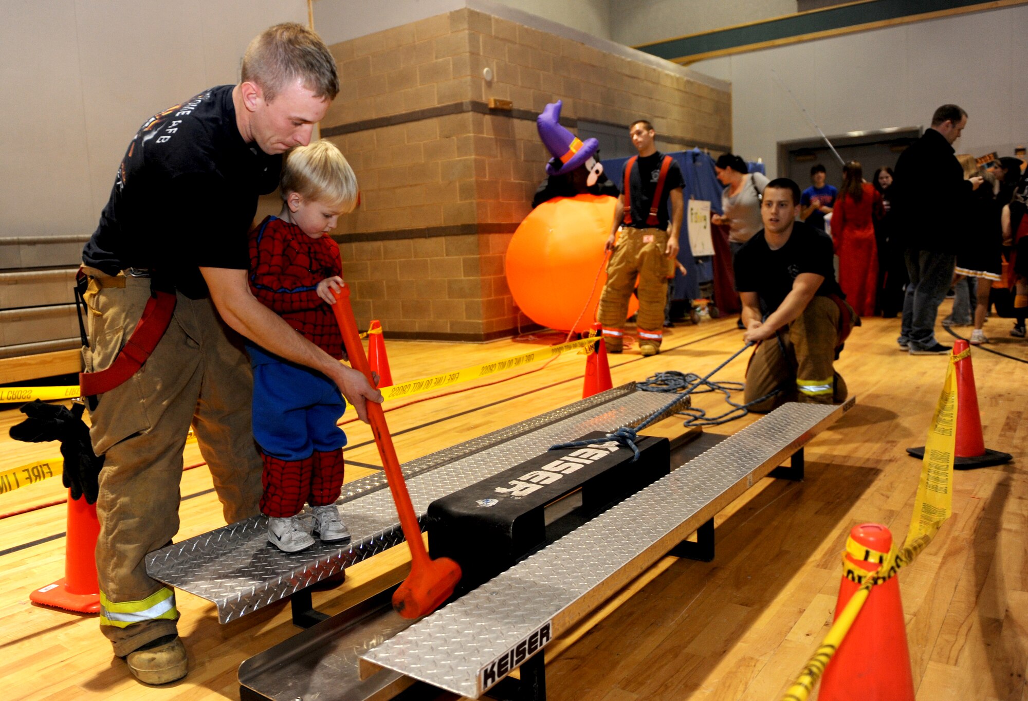 MOUNTAIN HOME AIR FORCE BASE, Idaho -- Airman Michael Harrington, 366th Civil Engineer Squadron base firefighter, helps Drake, age 2, complete a fireman's obstacle course Oct. 24 at the youth center's annual Boo Bash celebration. More than 750 Gunfighters and family members took part in this year's event. (U.S. Air Force photo by Senior Airman Samantha S. Crane)