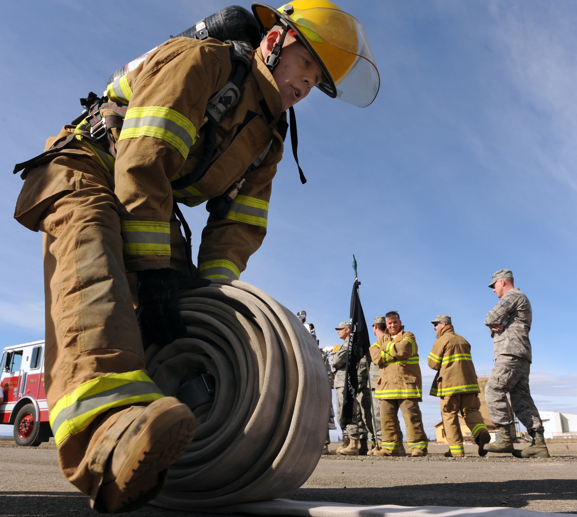 MOUNTAIN HOME AIR FORCE BASE, Idaho -- Airman 1st Class Ronald Holverson, 366th Logistics Readiness Squadron Petroleum, Oils and Lubricants team member, rolls up a hose as part of the first annual Fire Muster Challenge Oct. 23. Six teams competed in the timed challenge that consisted of five events. 366th LRS came in first place with a time of 2:53, 366th Civil Engineer Squadron explosive ordnance disposal came in second with a time of 3:18 and in third place was the senior noncommissioned officers with a time of 3:31. The fire department ultimately won the championship round with a time of 2:38. (U.S. Air Force photo by Airman 1st Class Debbie Lockhart)