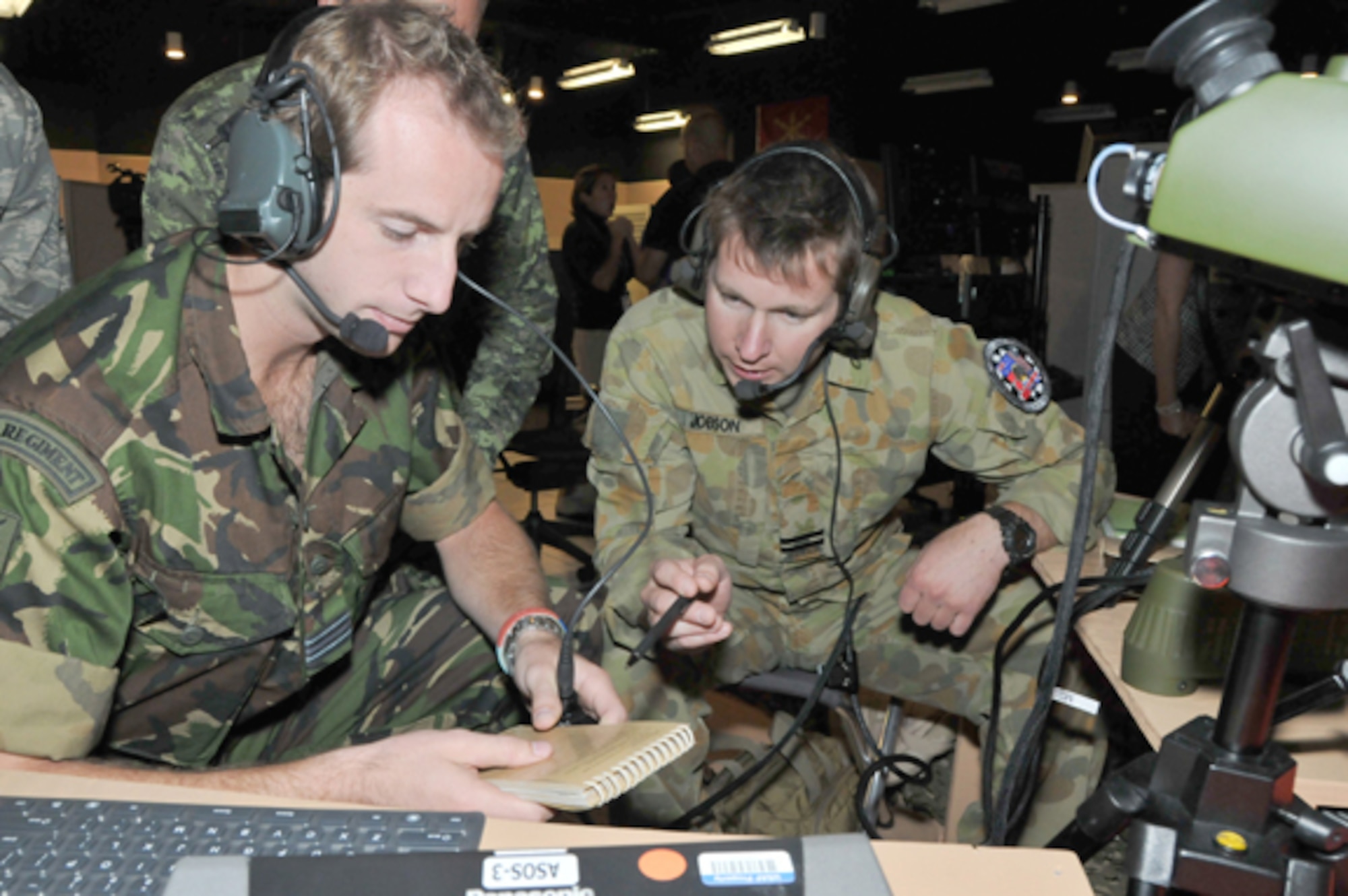 KIRTLAND AIR FORCE BASE, N.M. -- British JTAC Flight Lieutenant Matthew Jupp and a Royal Australian Air Force JTAC Flight Lieutenant Sean Jobson discuss procedures during the exercise at the Distributed Mission Operations Center on Sept. 23. Coalition Virtual Flag 09-4 was the first ever exercise to integrate four coalition forces and air assets, and U.S. joint forces in a virtual air battle spanning operational- and tactical-level warfare. (Air Force photo by Ken Moore)