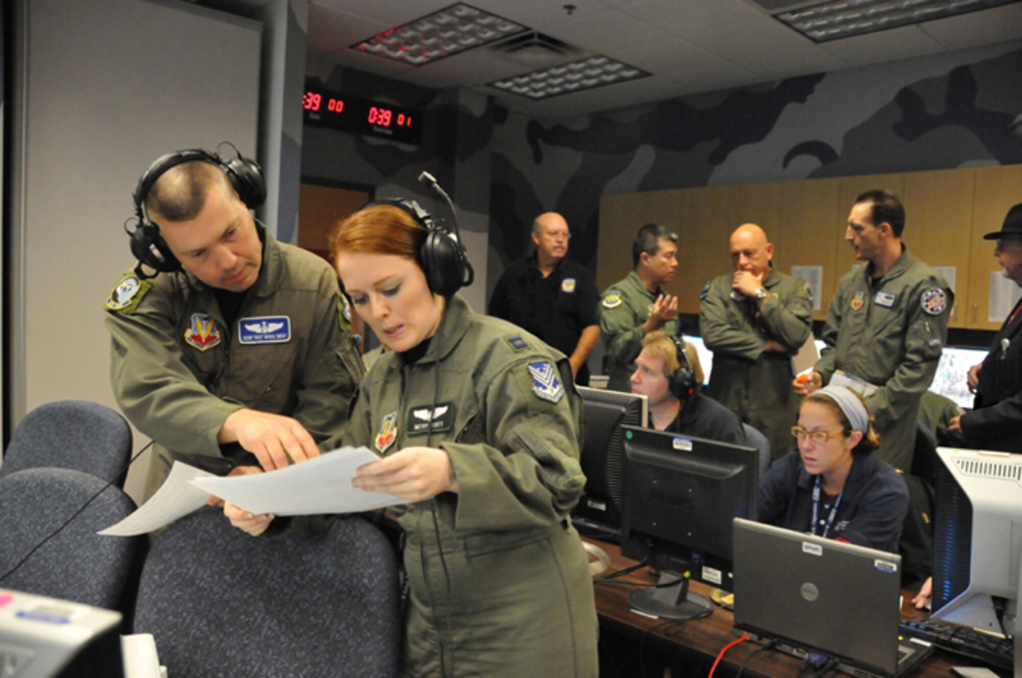 KIRTLAND AIR FORCE BASE, N.M. -- Senior Master Sgt. Kevin McRae and Capt. Betsy Scott discuss data during Coalition Virtual Flag at the Distributed Mission Operations Center on Sept. 18. Capt. Scott, who is a Joint Surveillance and Target Attack Radar System air weapons officer, was working ton he white force during the exercise. The white force adds constructive entities into the virtual battlespace. (Air Force photo by Ken Moore)